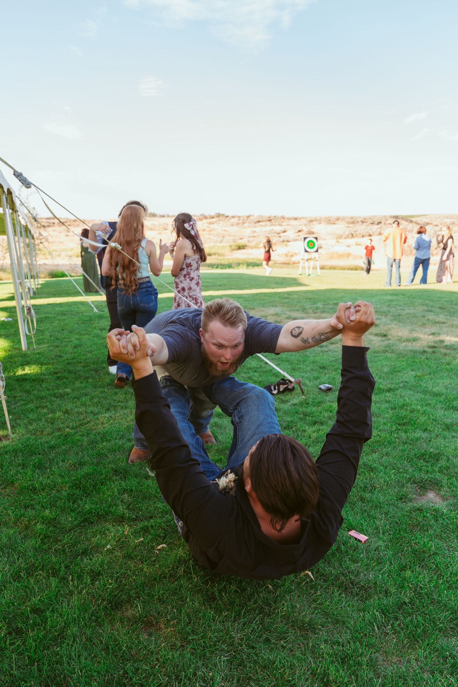 A sequence of playful somersaults captured on green grass during an outdoor celebration.
