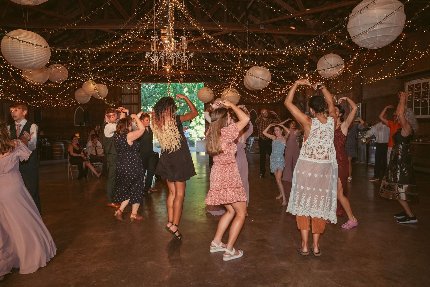 Festive dance party with guests moving beneath twinkling lights and paper lanterns.