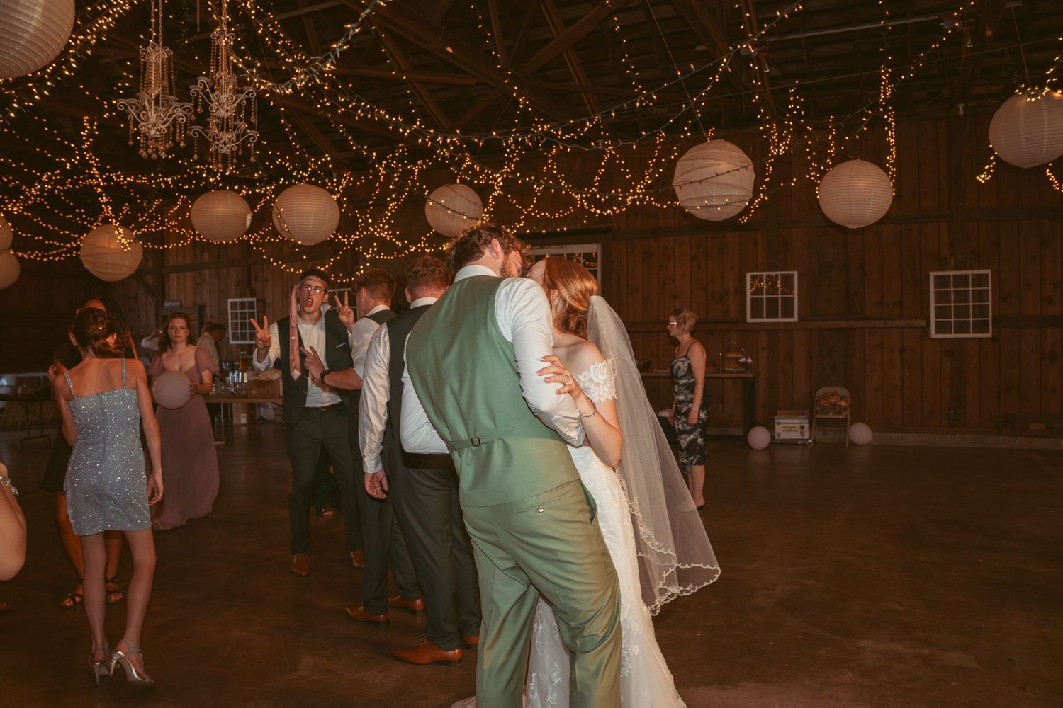 Guests dancing and celebrating at an evening wedding reception with decorative lighting.