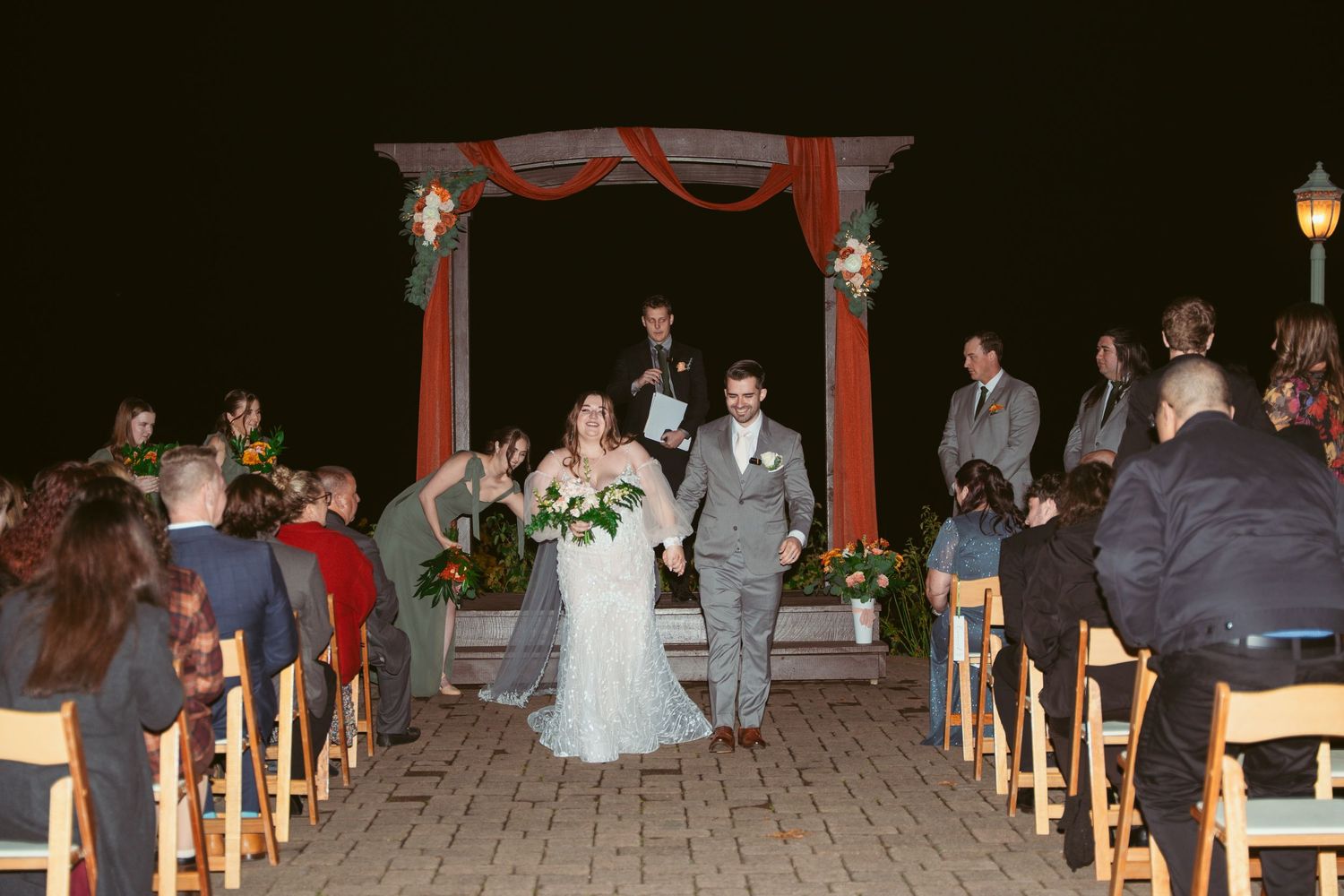 Wedding couple celebrating at the altar while guests cheer from wooden chairs.