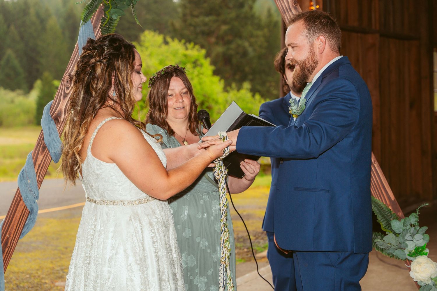 Romantic exchange between couple during barn wedding ceremony with guests looking on.