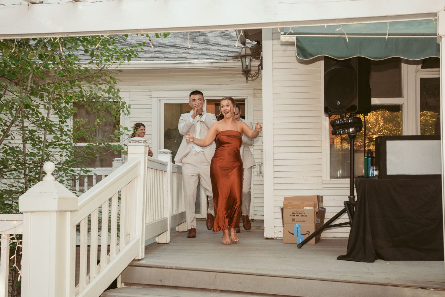 Couple making their entrance onto a white porch during a wedding celebration.