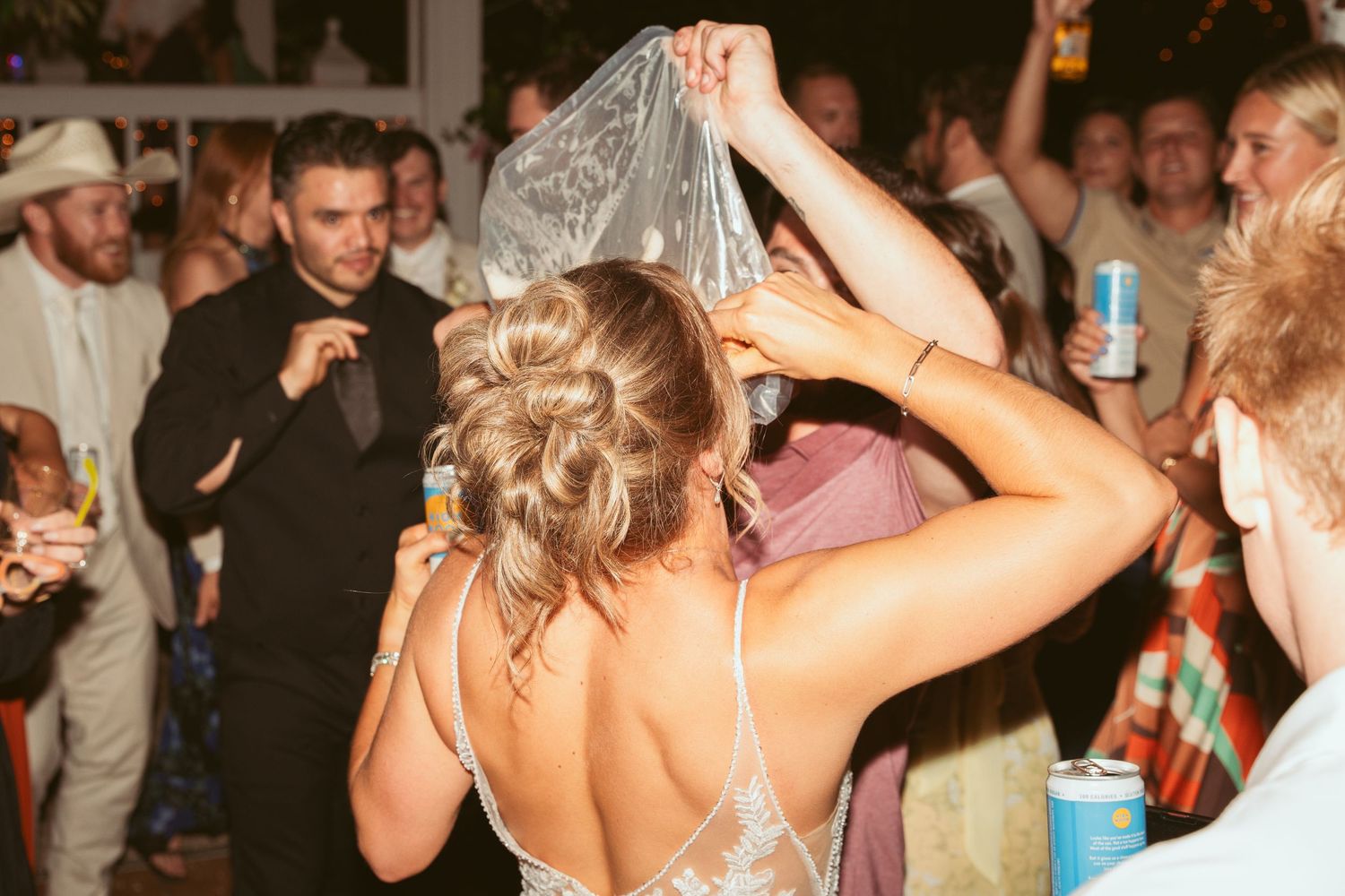 A bride in a sparkly dress dances energetically at her wedding reception.