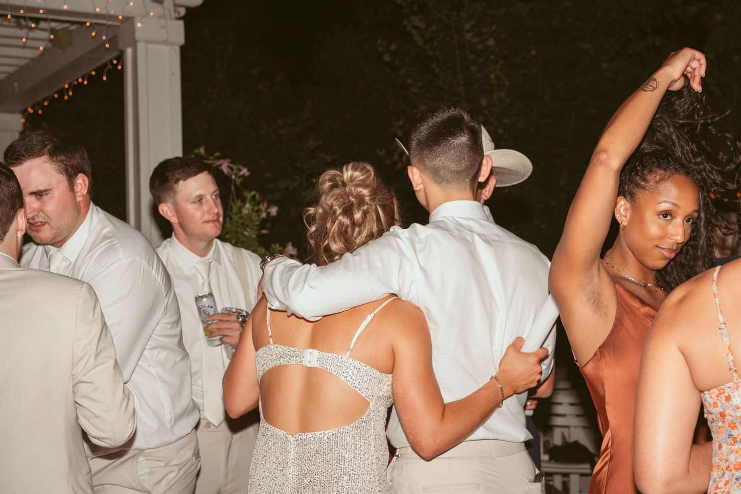 Wedding guests dancing energetically on a packed dance floor at night.