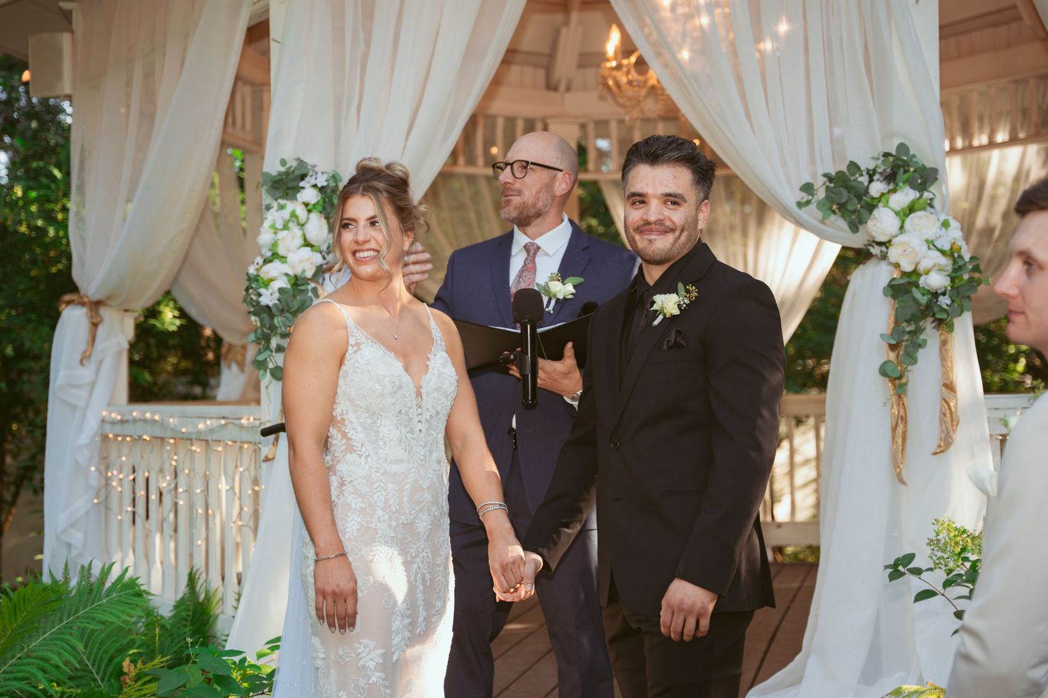 Wedding ceremony setup with white drapes and floral arrangements in an elegant outdoor venue.