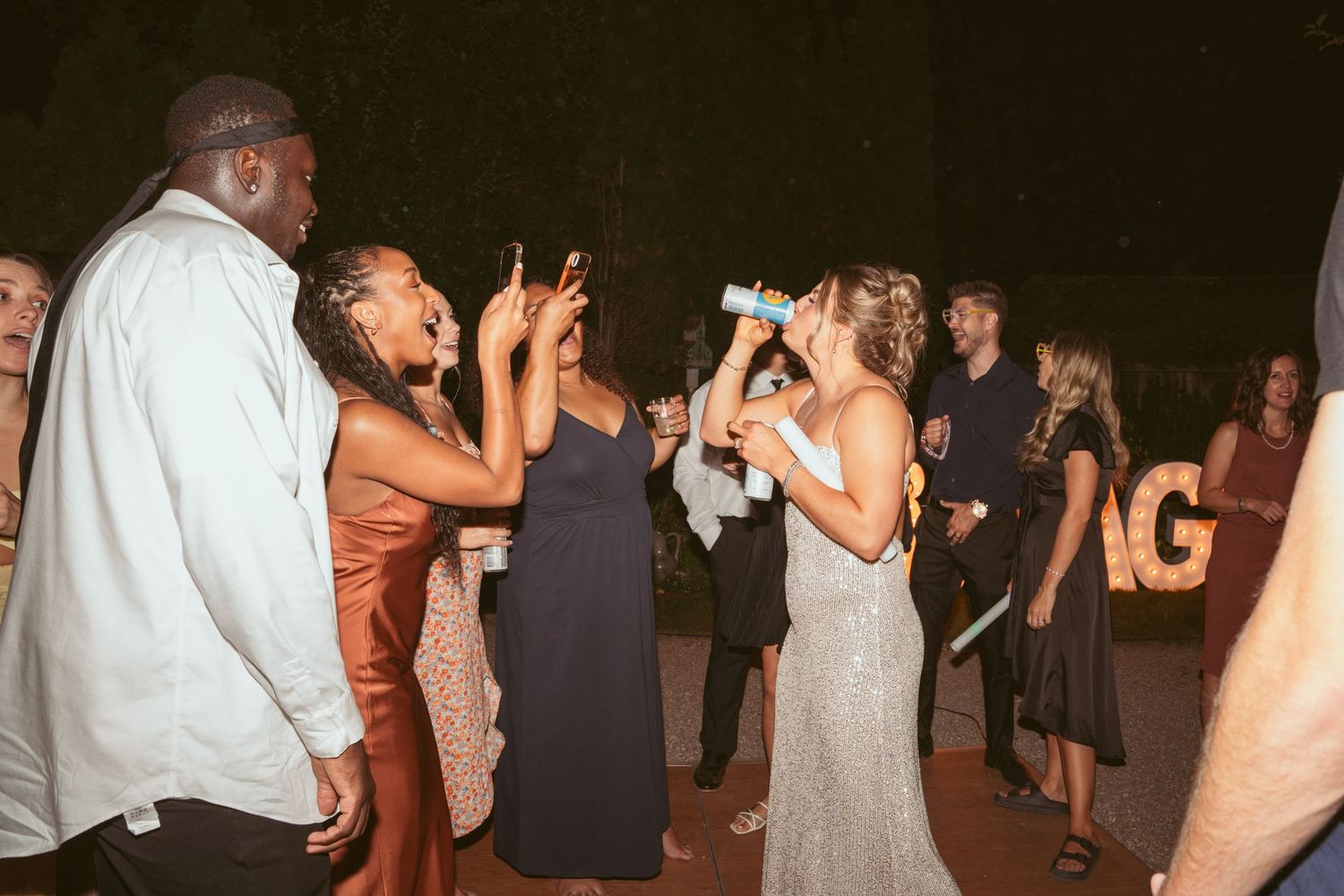 Wedding guests dancing and celebrating at an outdoor evening reception.