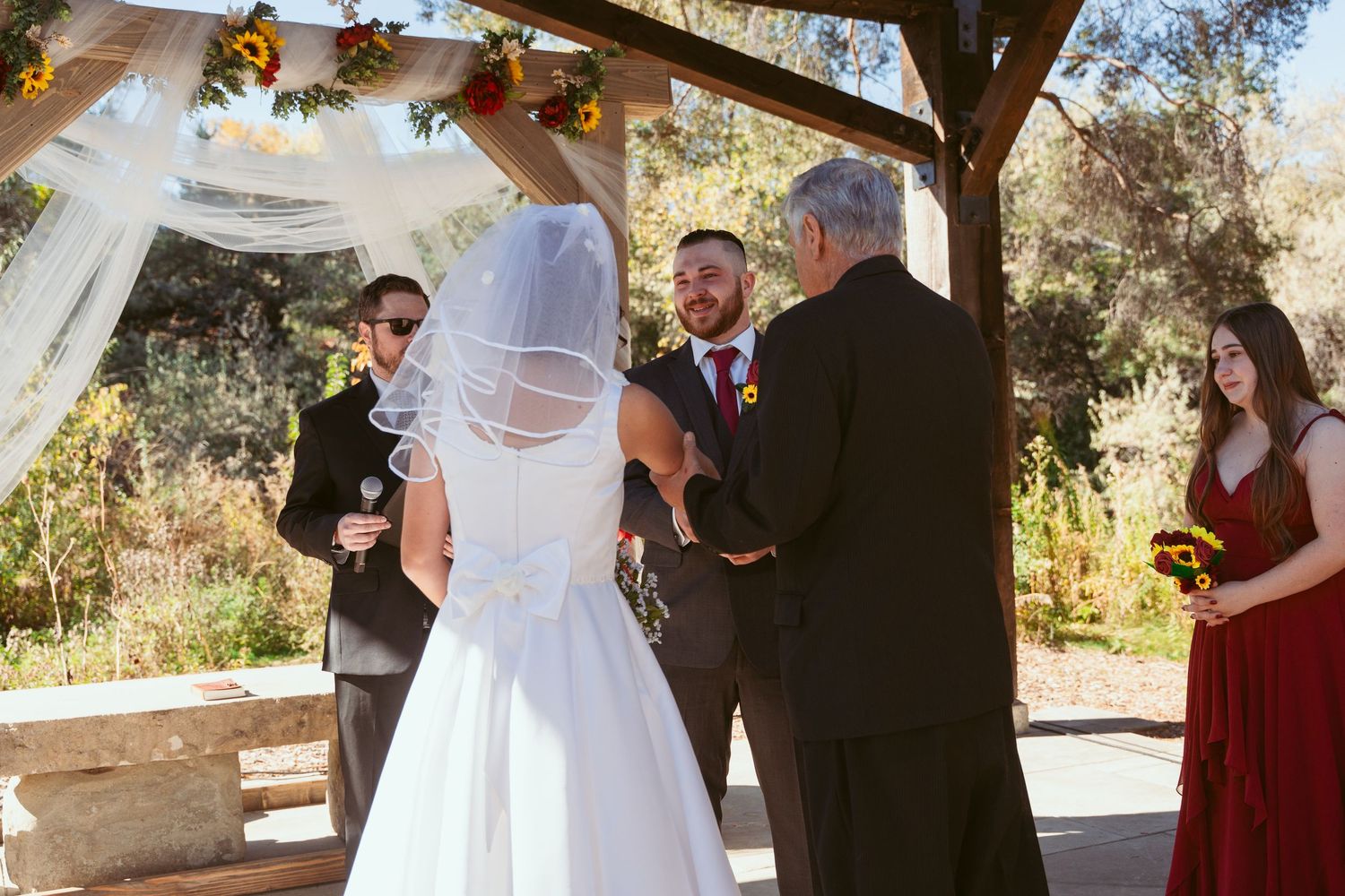 Wedding ceremony moments captured under wooden pergola with autumn scenery.