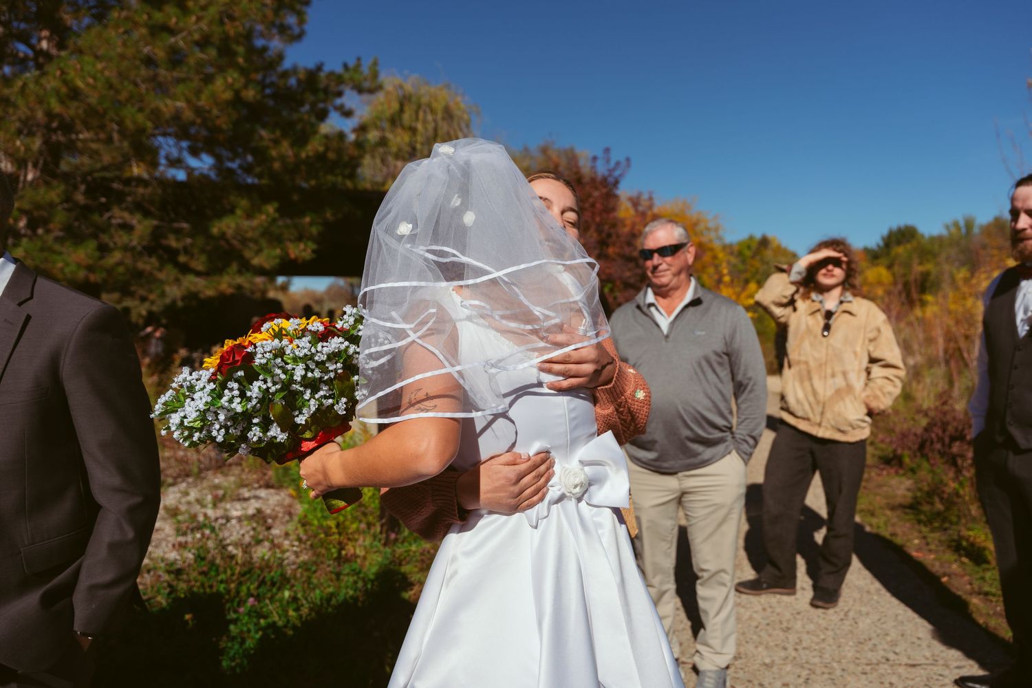 Outdoor wedding photography session with natural autumn backdrop and blue skies.