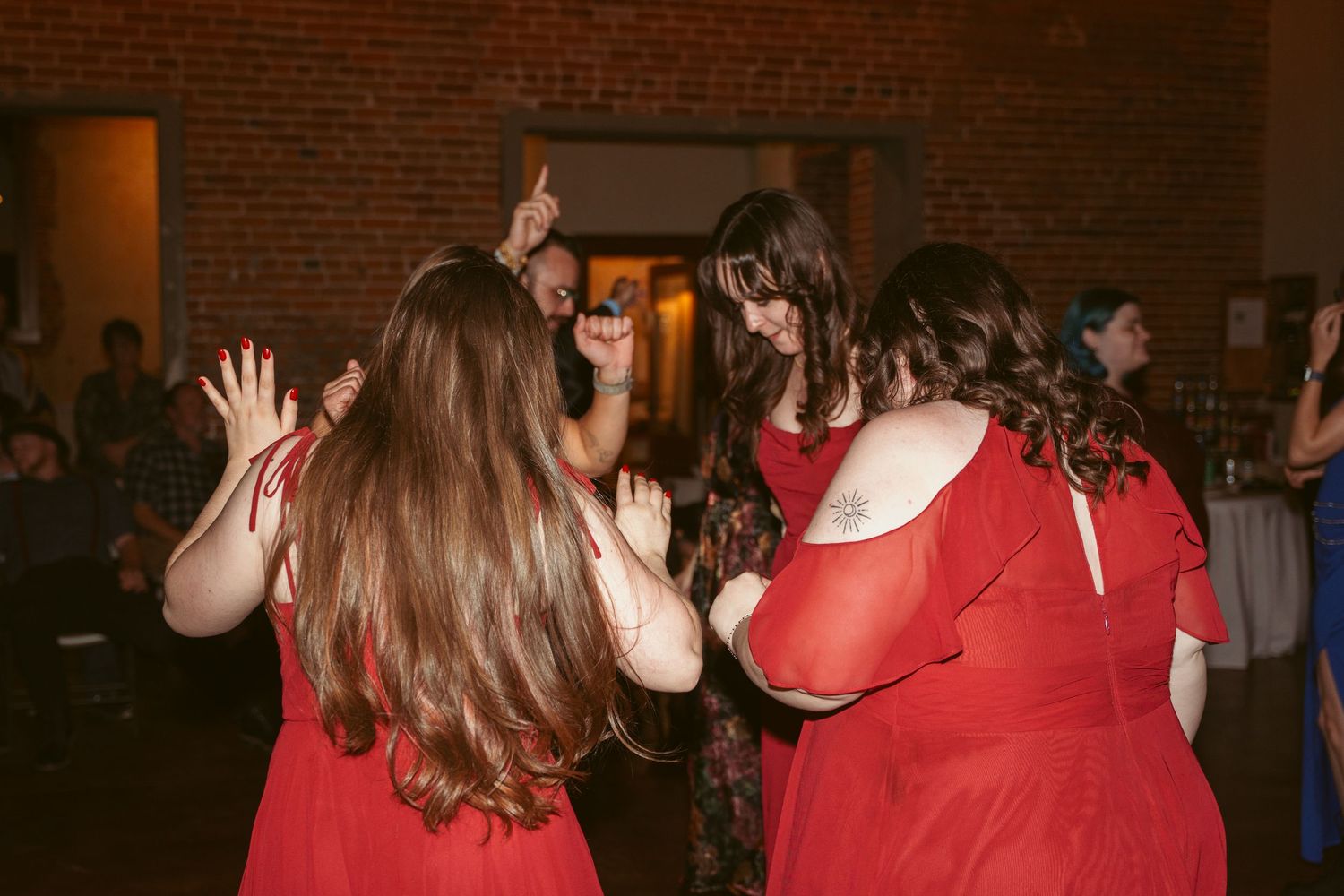 Wedding guests in red dresses dancing and celebrating on the dance floor.