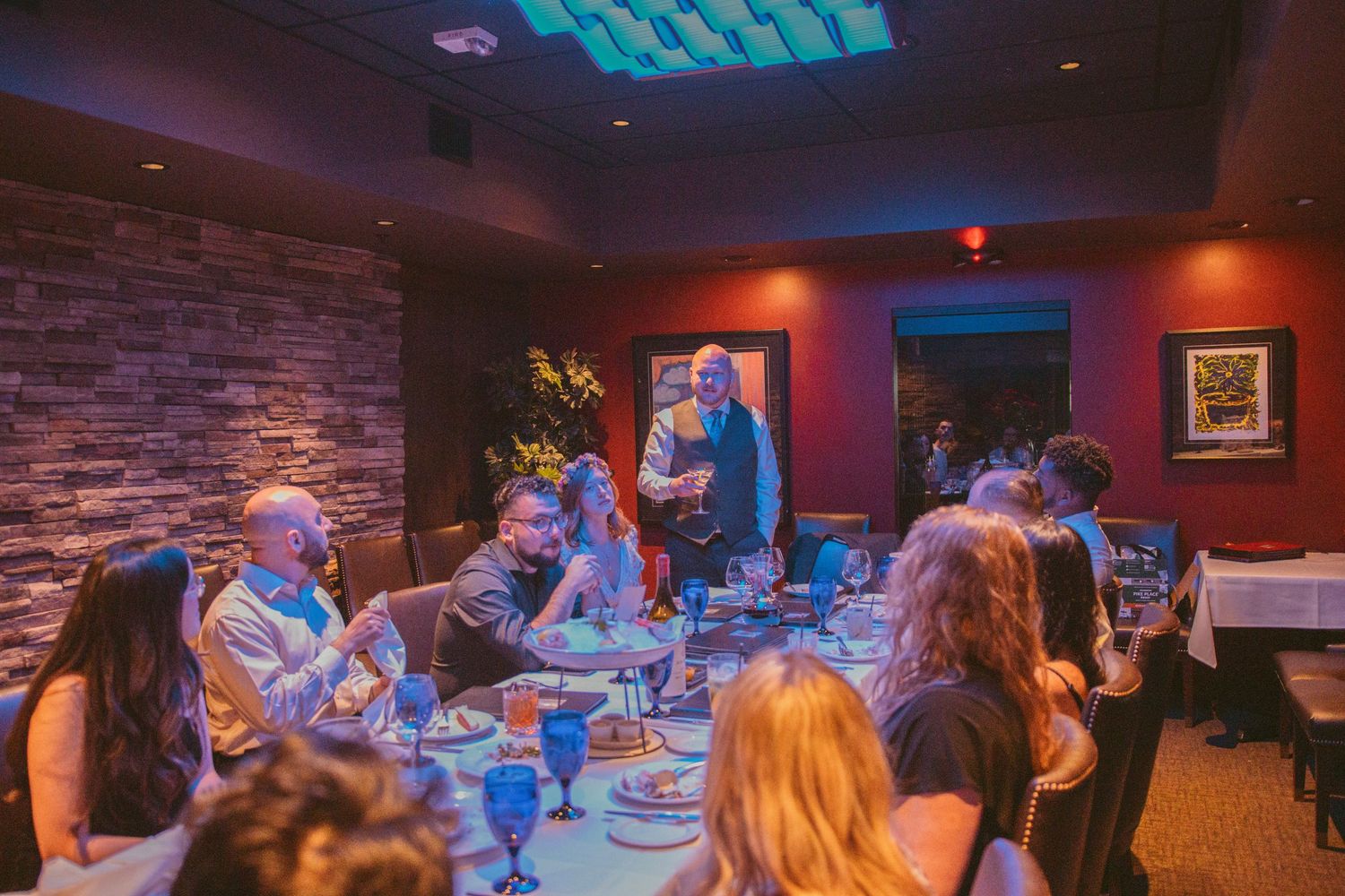 Wedding reception venue with exposed brick walls and blue ceiling lighting.