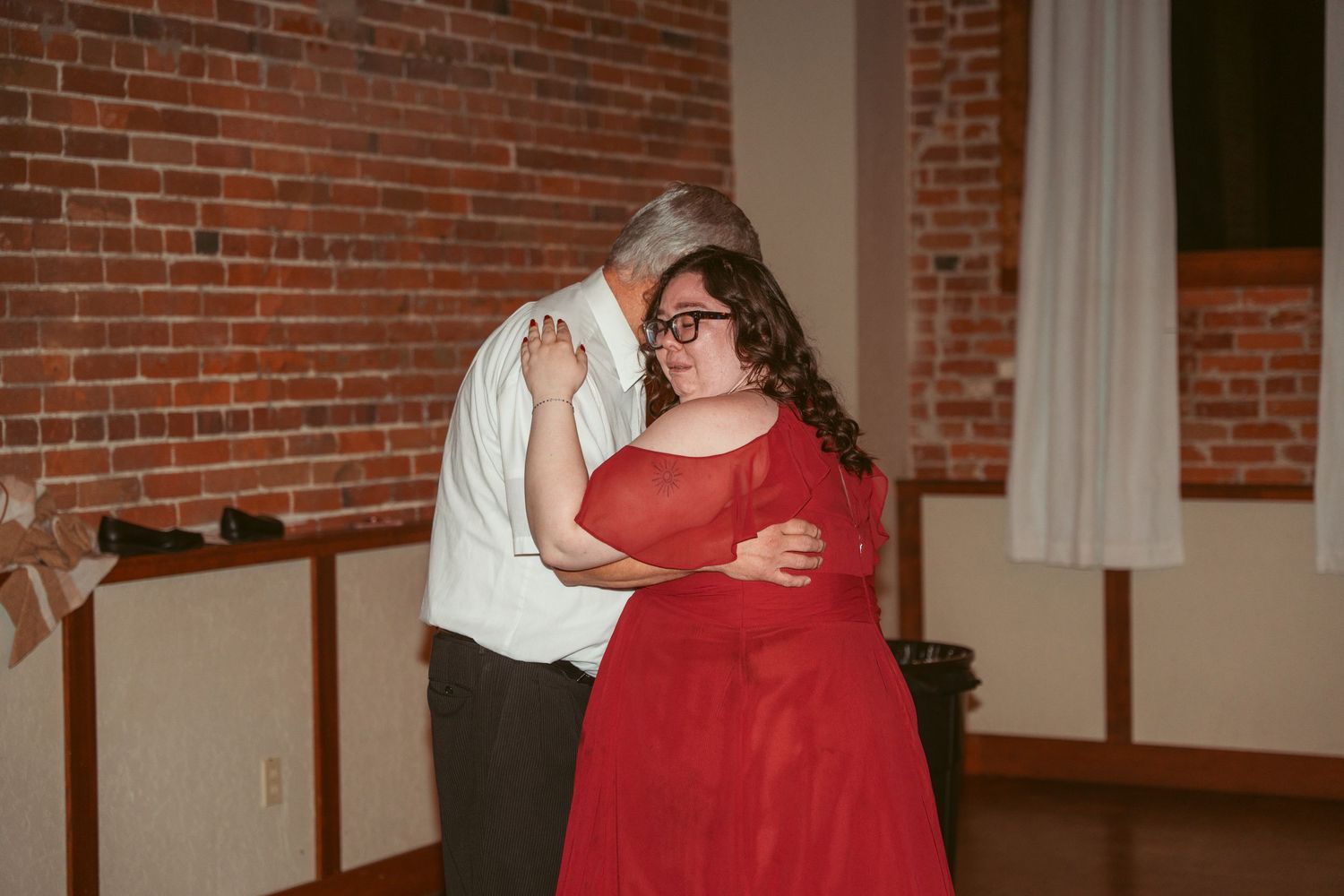 Dancing couples celebrate at a wedding reception in a rustic brick interior.