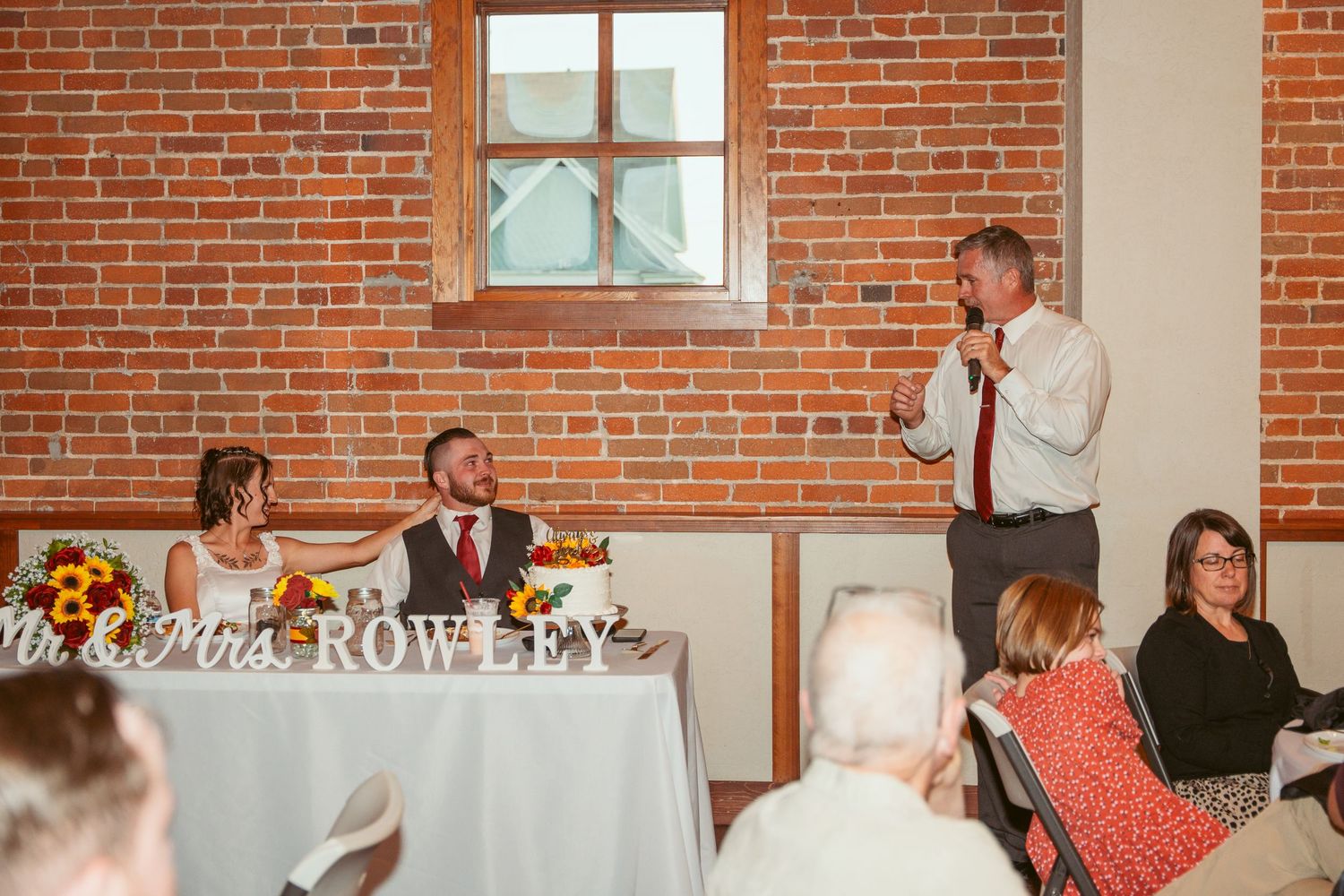 Wedding reception venue with exposed brick walls and string lights creating a warm, rustic atmosphere.