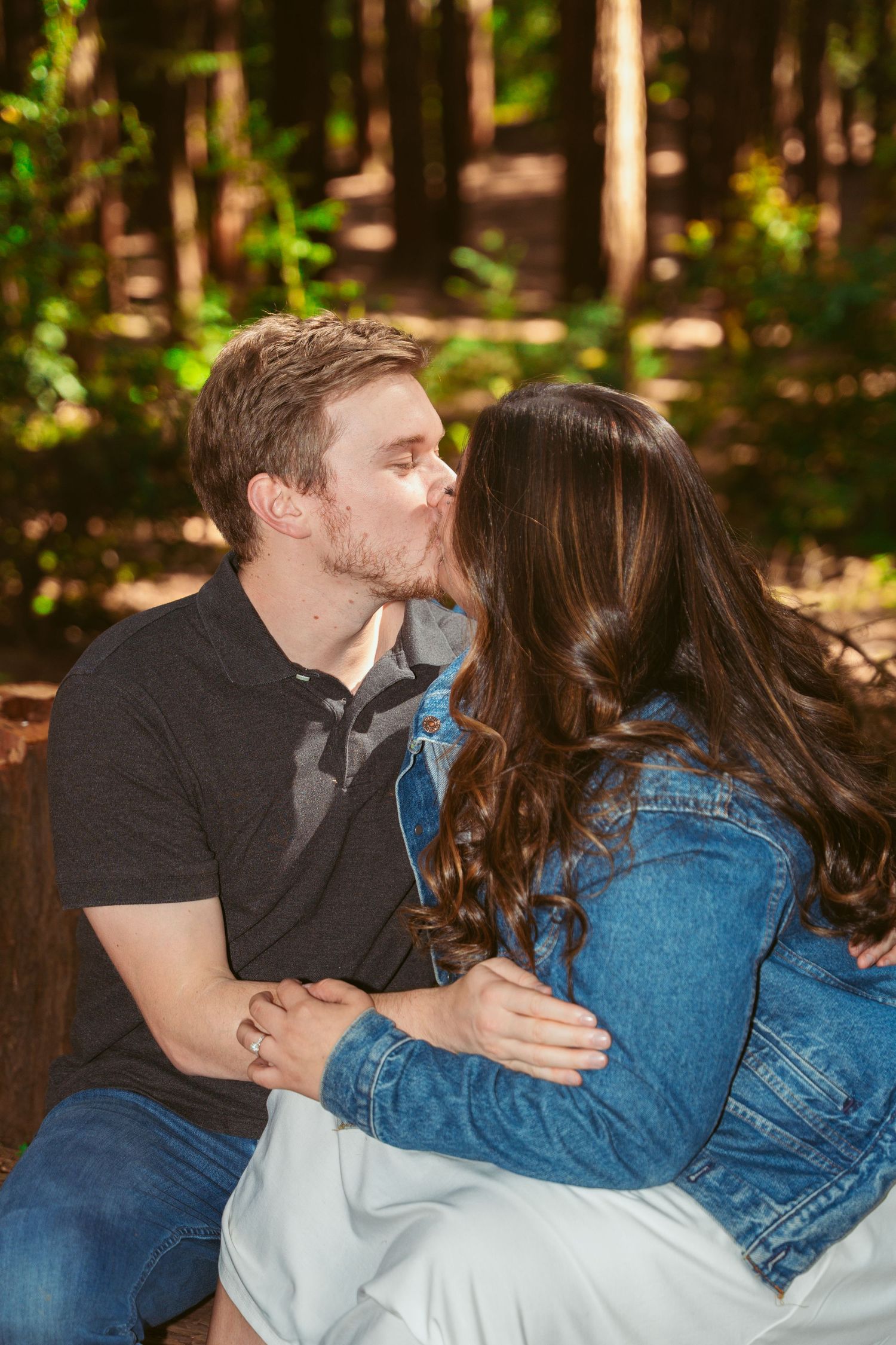 A sweet moment between a couple sitting together in a wooded area.