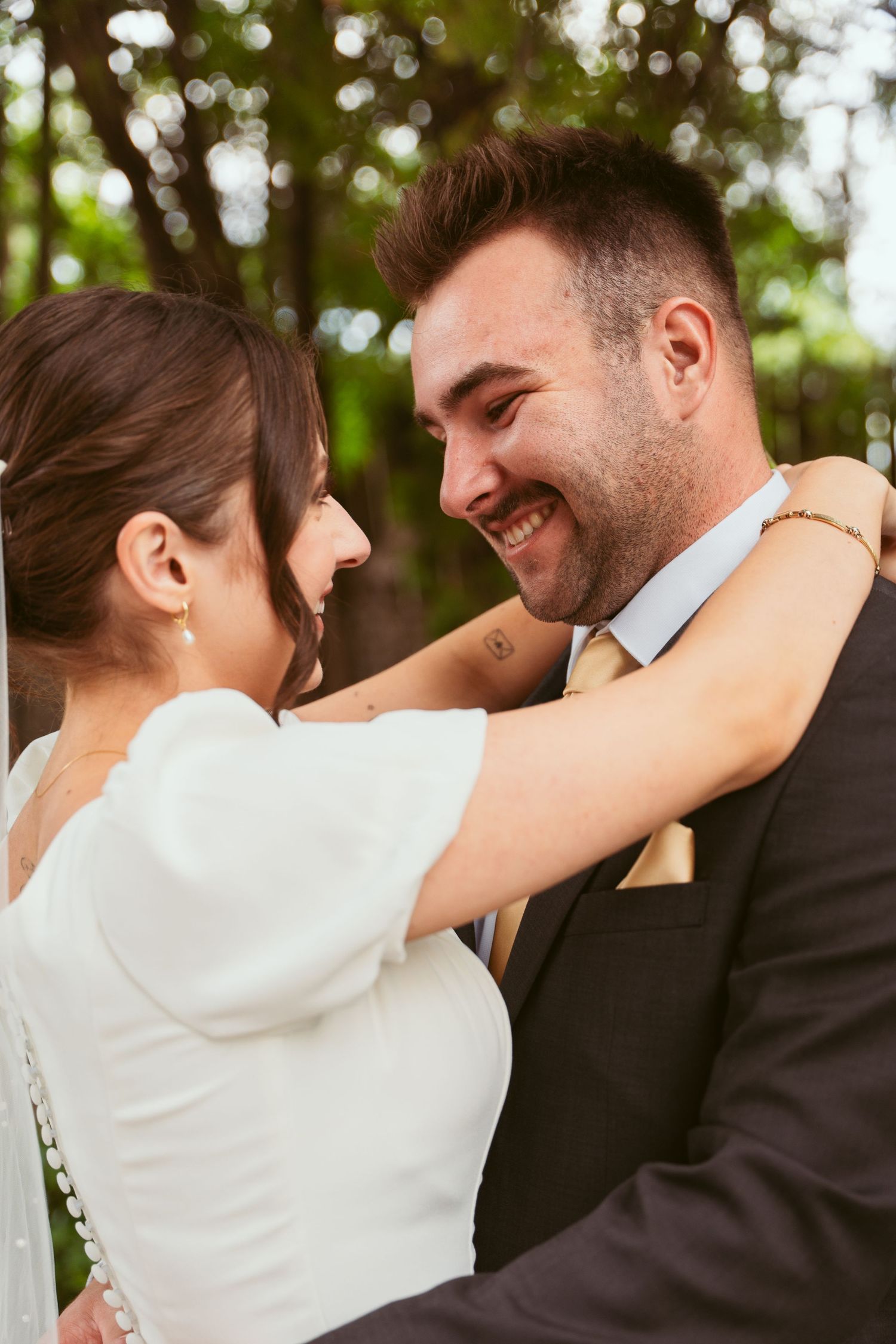 Romantic outdoor wedding portrait showing couple embracing and laughing together.