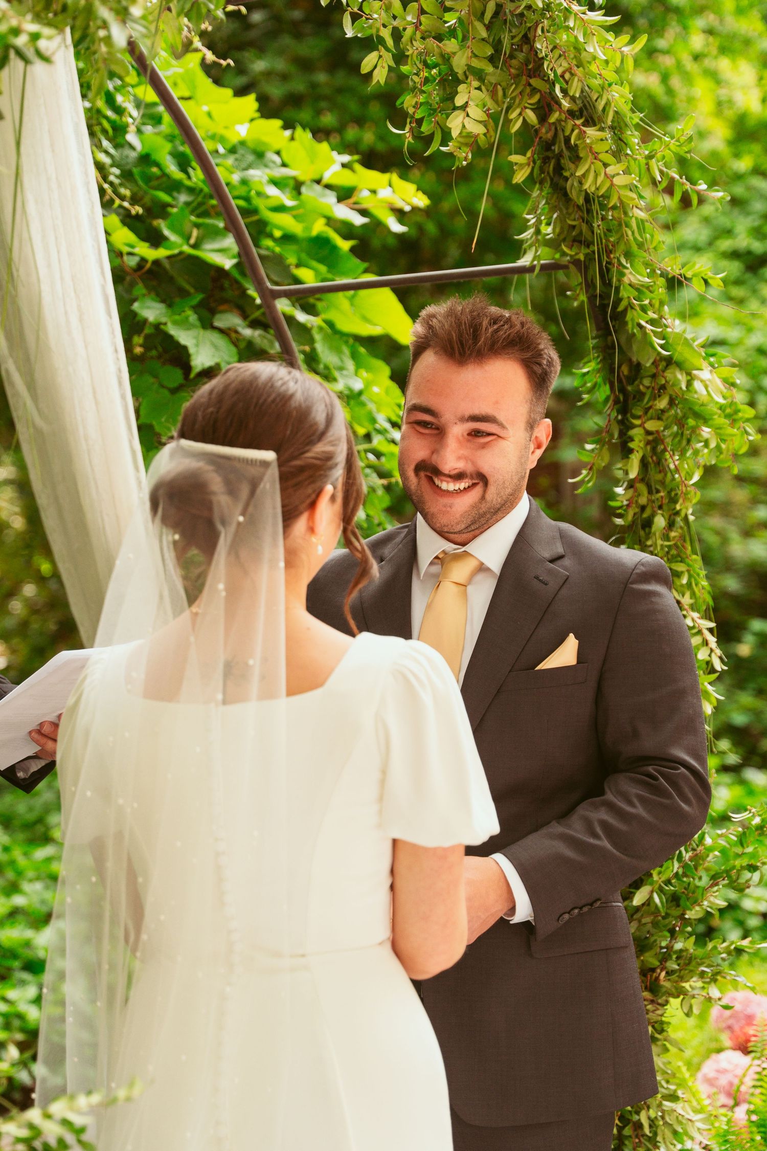 Wedding ceremony moment in a lush garden setting with white decor.