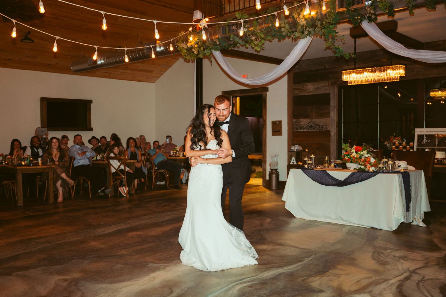 Wedding reception venue with string lights and white drapes creating a romantic atmosphere.