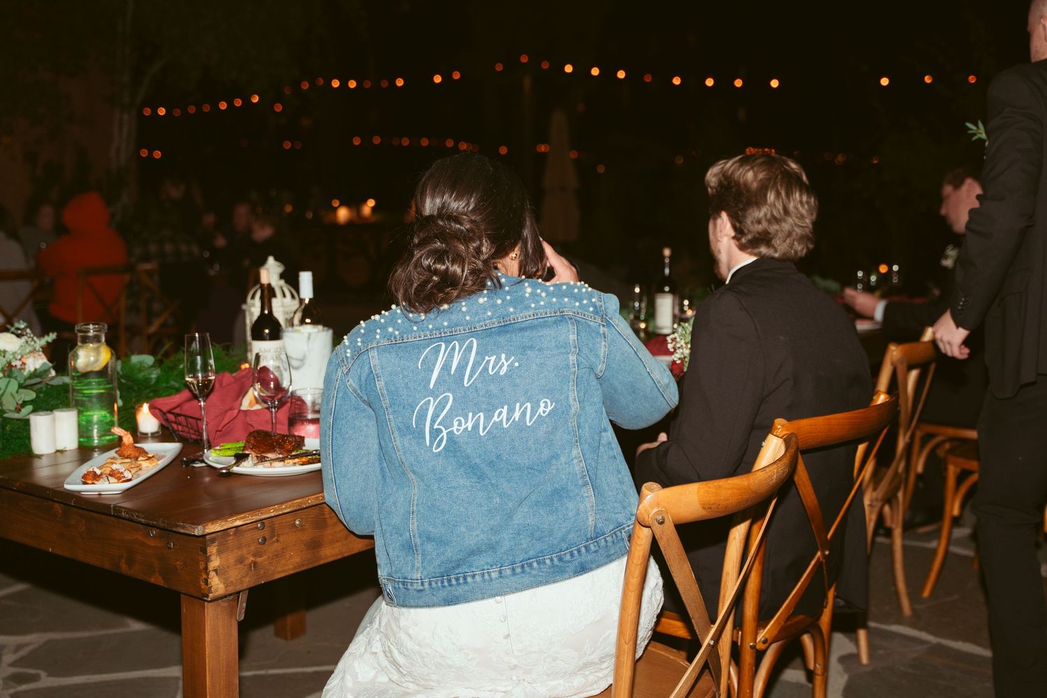 A romantic first dance at an outdoor evening wedding reception with string lights overhead.