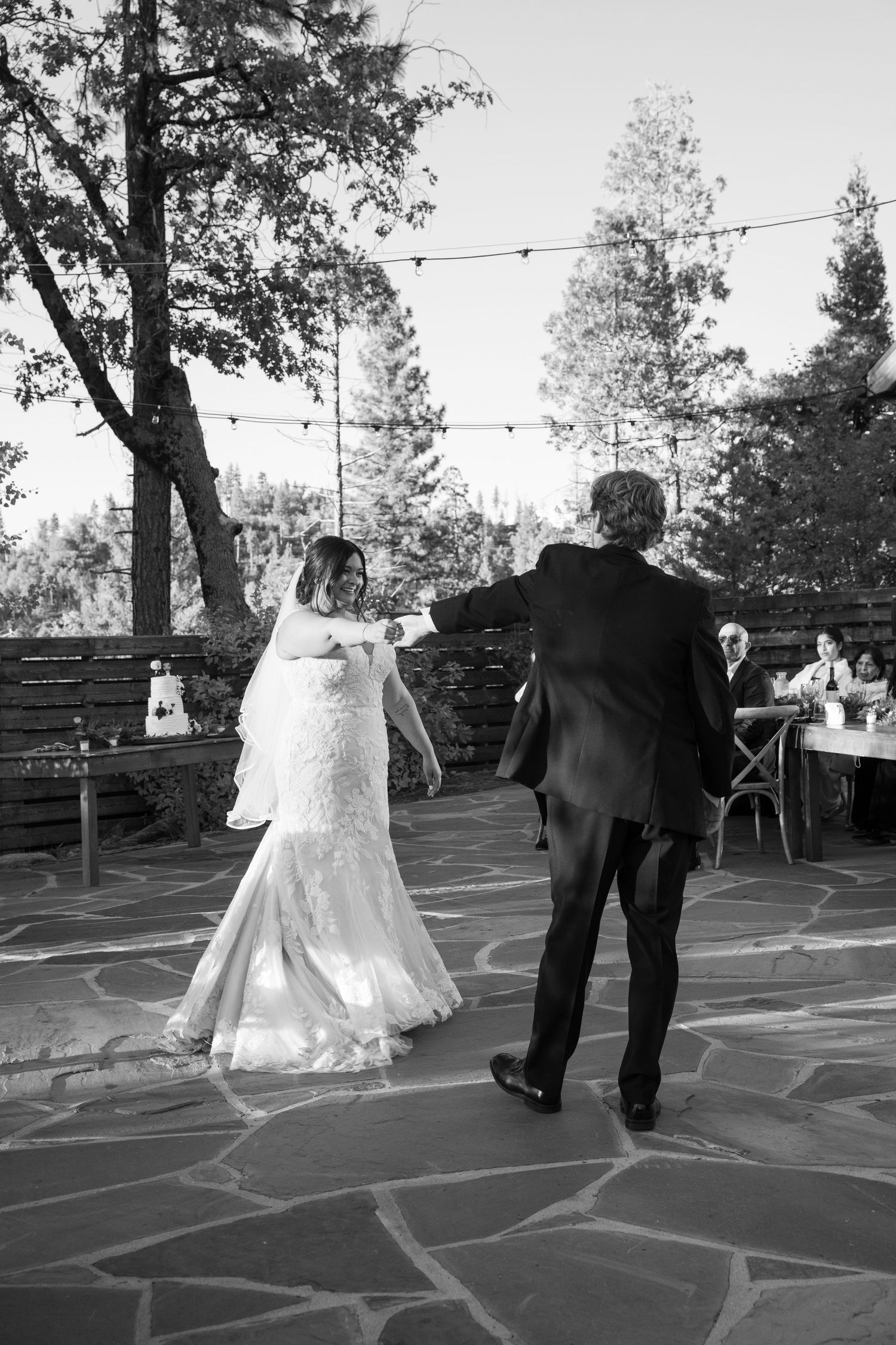 Black and white photos of a couple dancing on a stone patio during their wedding reception.