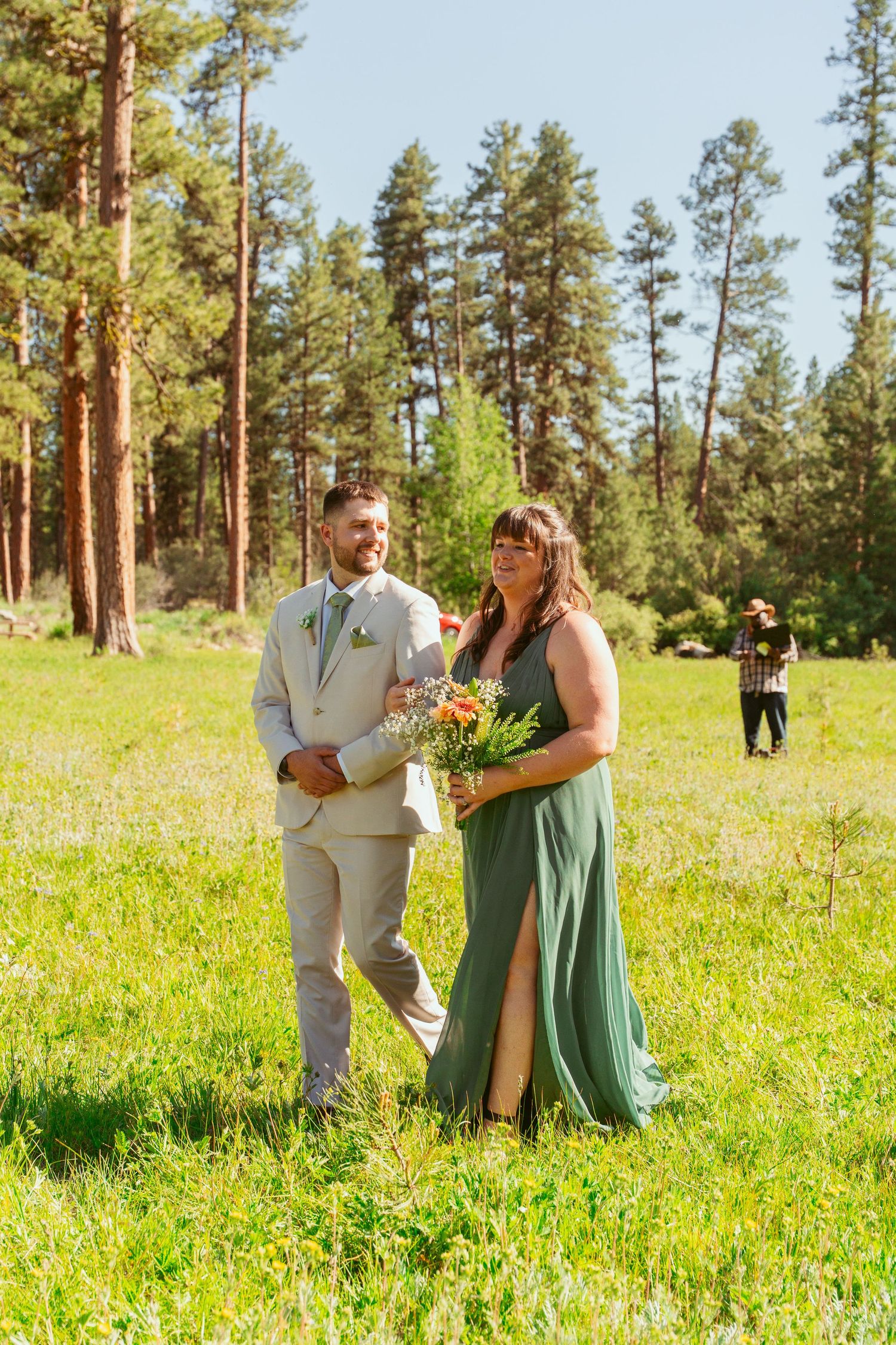 Couple shares intimate moment in a wildflower meadow with pine trees in the background.