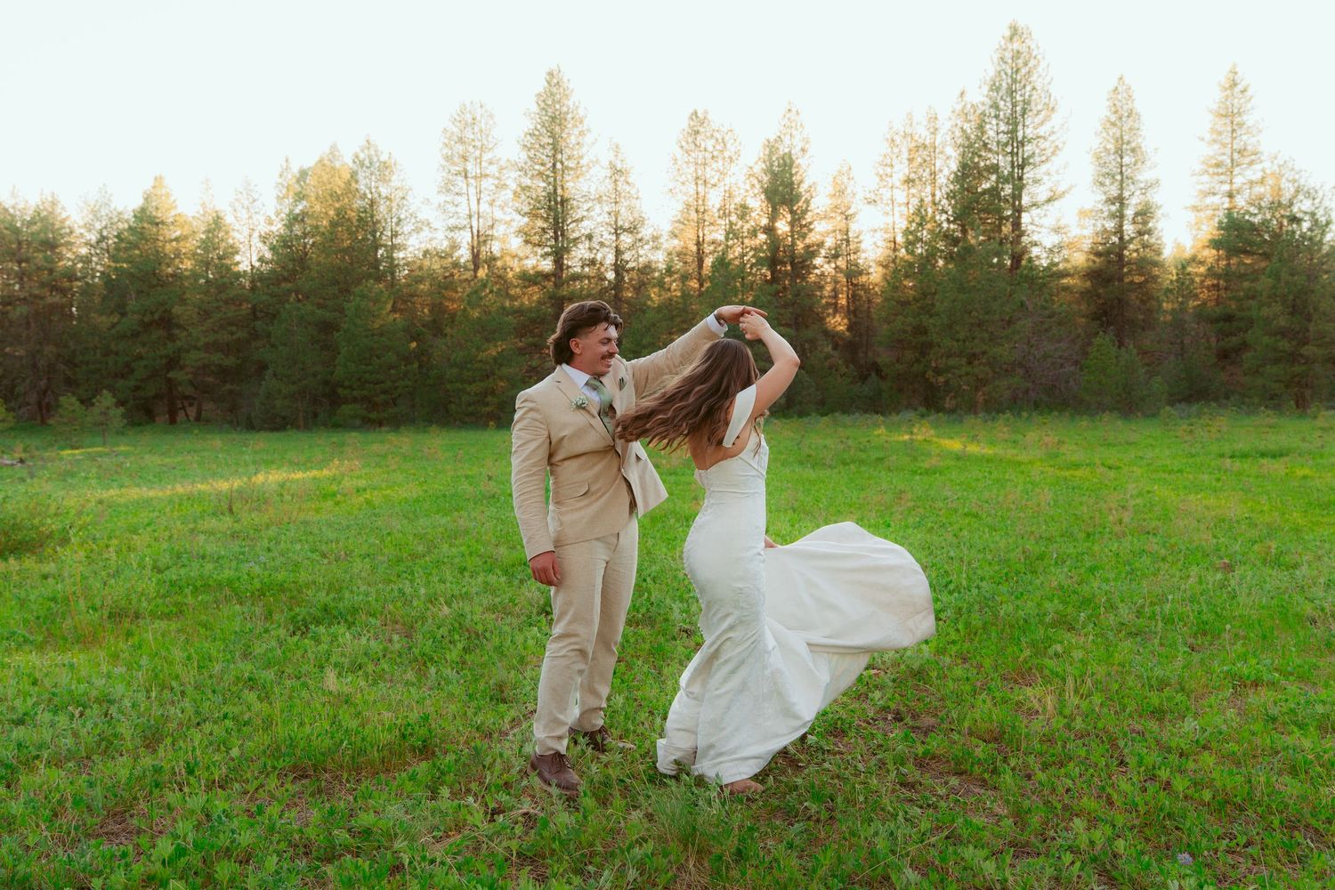 Dancing couple celebrating in formal attire against a forest backdrop.