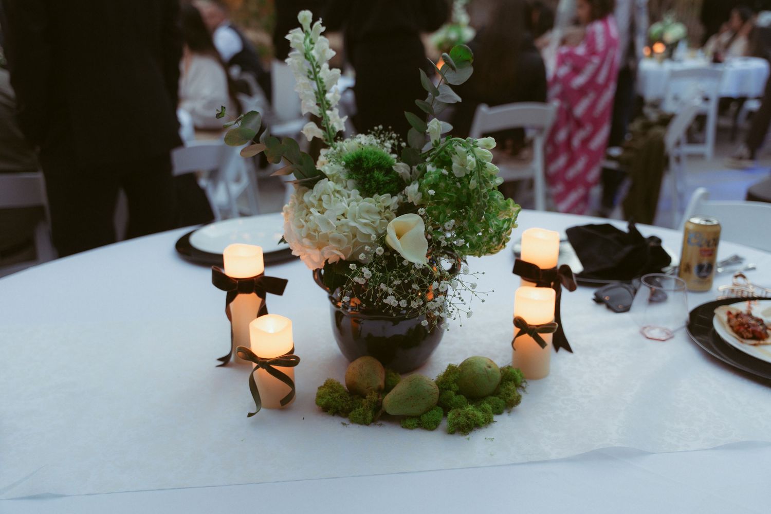 Wedding reception tables decorated with greenery and candlelight at dusk.