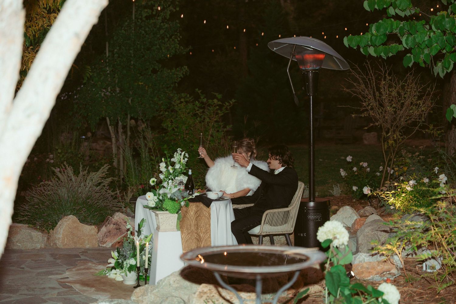 Garden reception area decorated with hanging lights and floral arrangements.