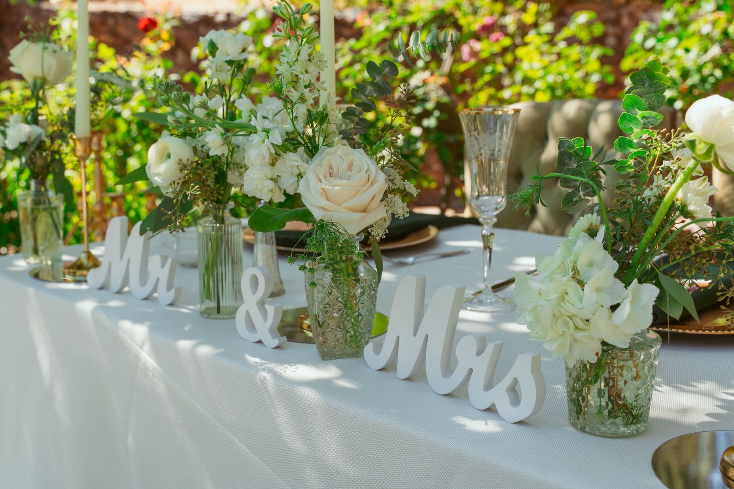 Wedding reception table decorated with white flowers and 'Mr & Mrs' signage.