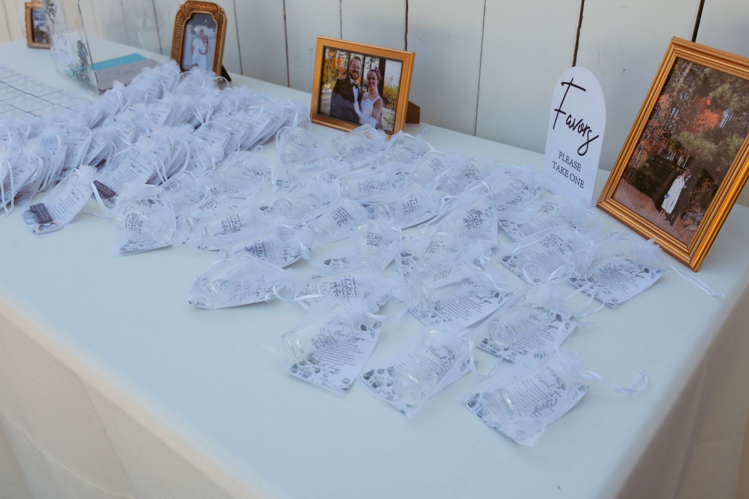 Wedding reception check-in table with framed photos and white decor.