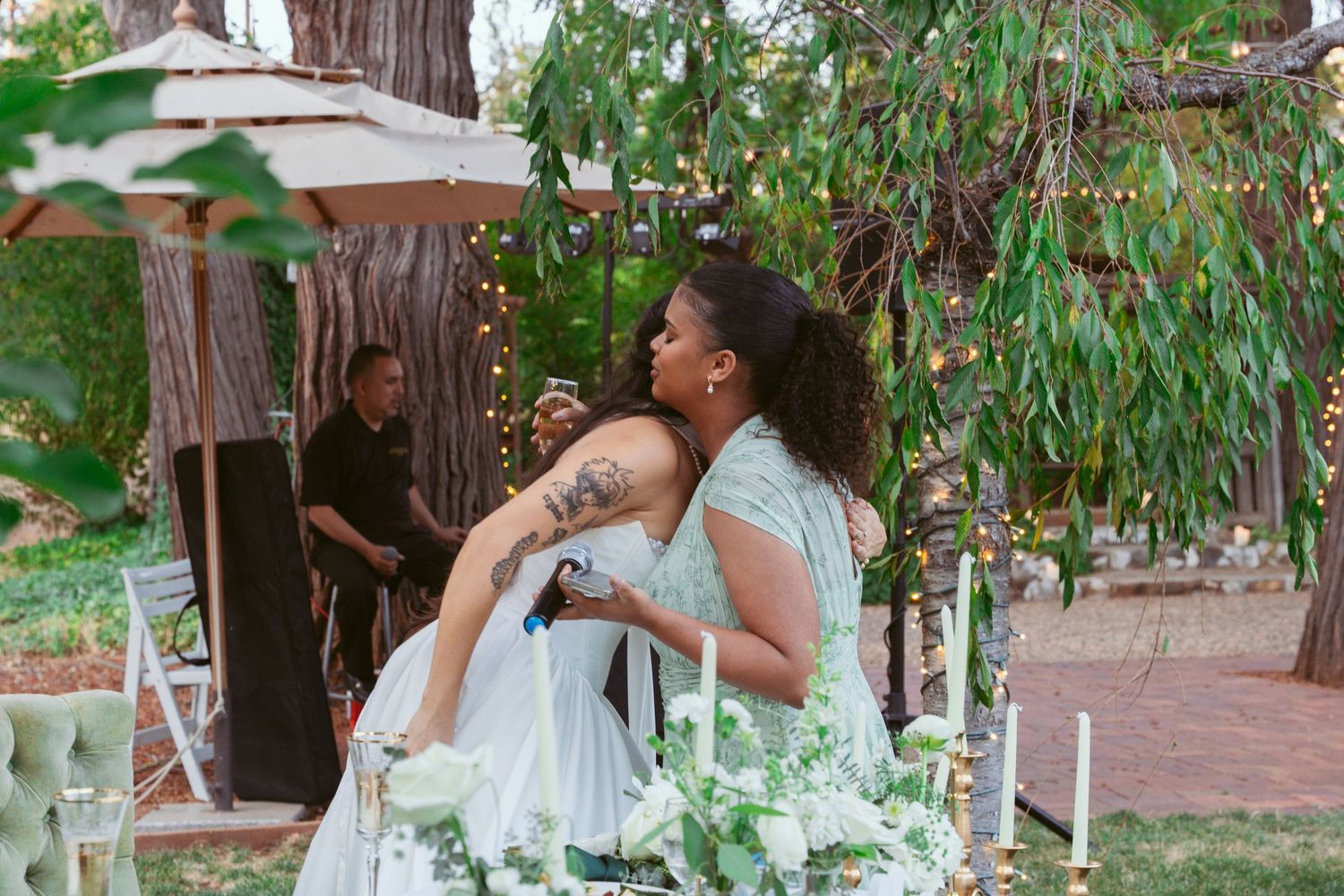 Wedding guests dance and celebrate under string lights at an outdoor garden reception.