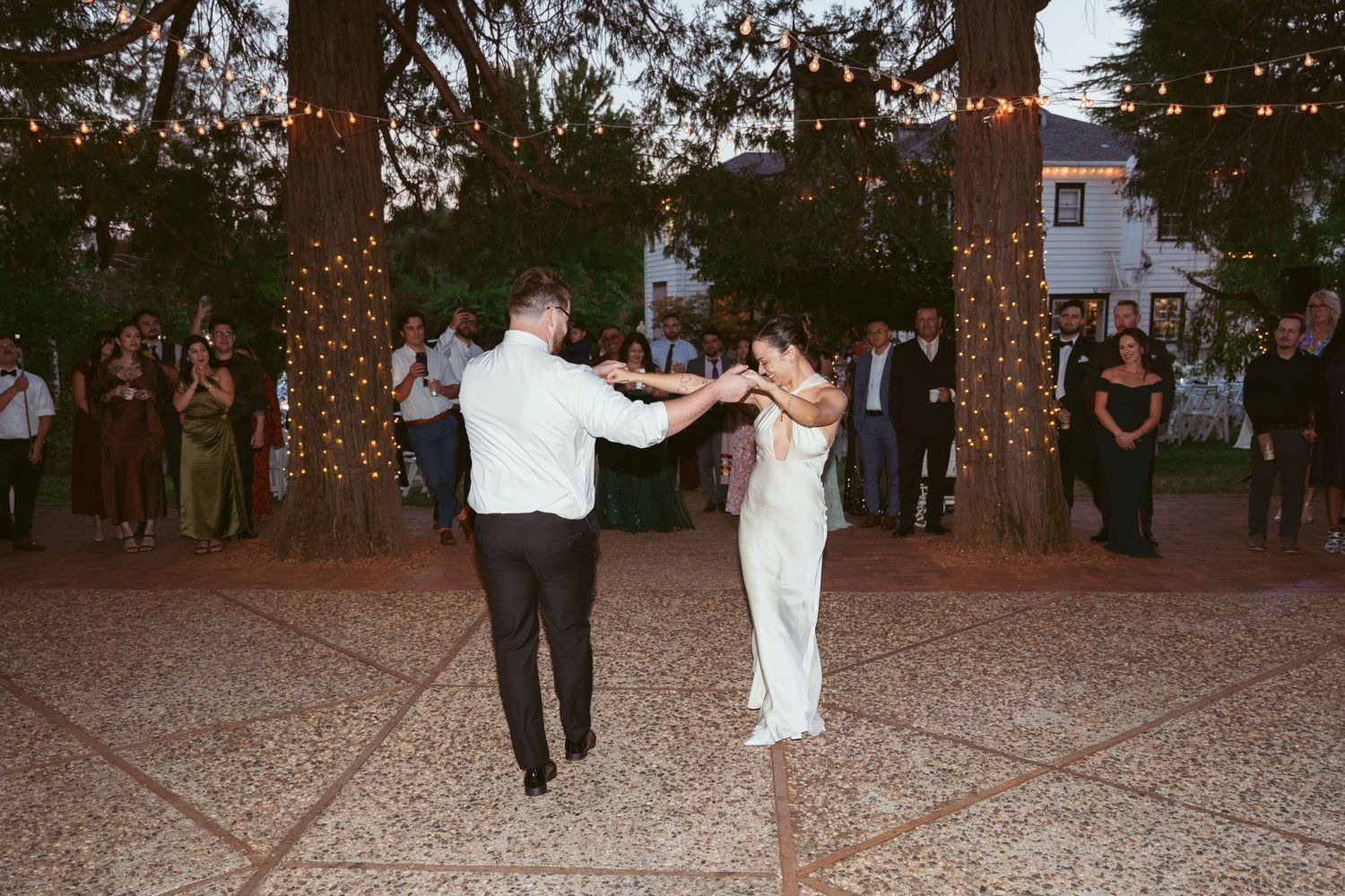 Wedding guests dancing on a gravel dance floor at an outdoor evening celebration.
