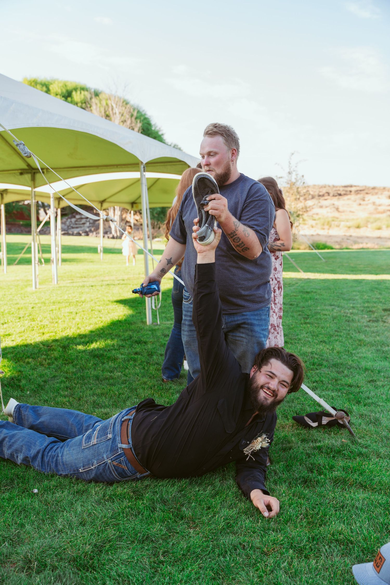 People having fun and playing on grass under a green canopy tent at an outdoor event.