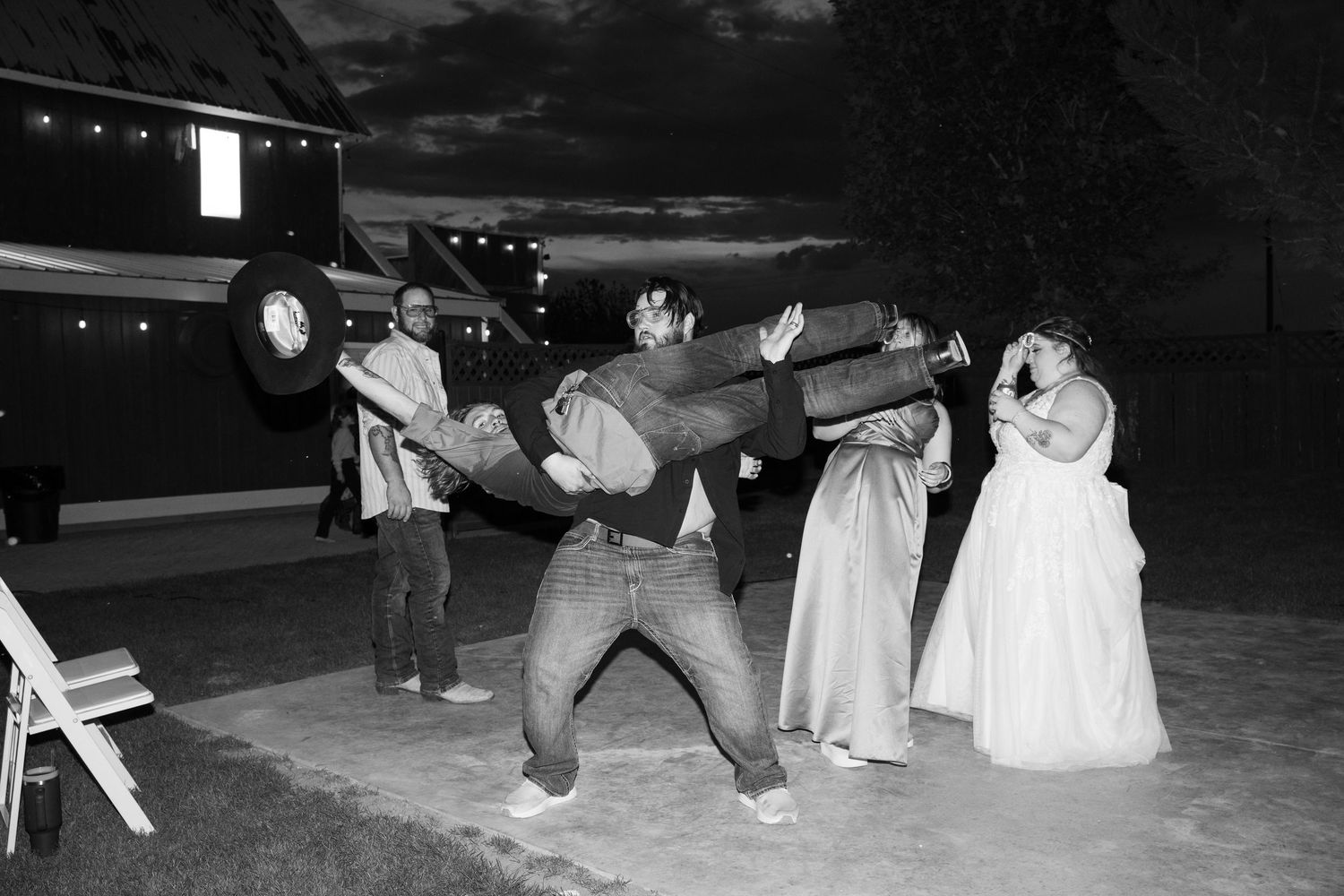Black and white photo of wedding guests performing synchronized dance moves.