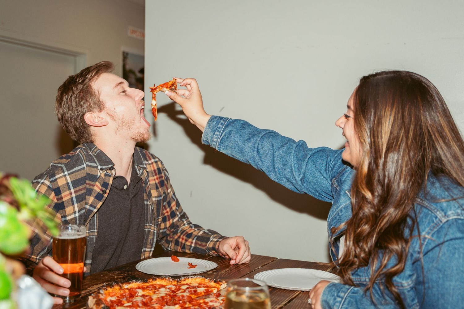 Friends enjoying pizza and beer at a cozy restaurant with wooden decor.