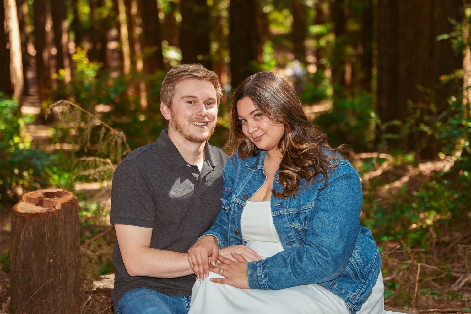 A joyful couple shares laughter while sitting together in a wooded park.