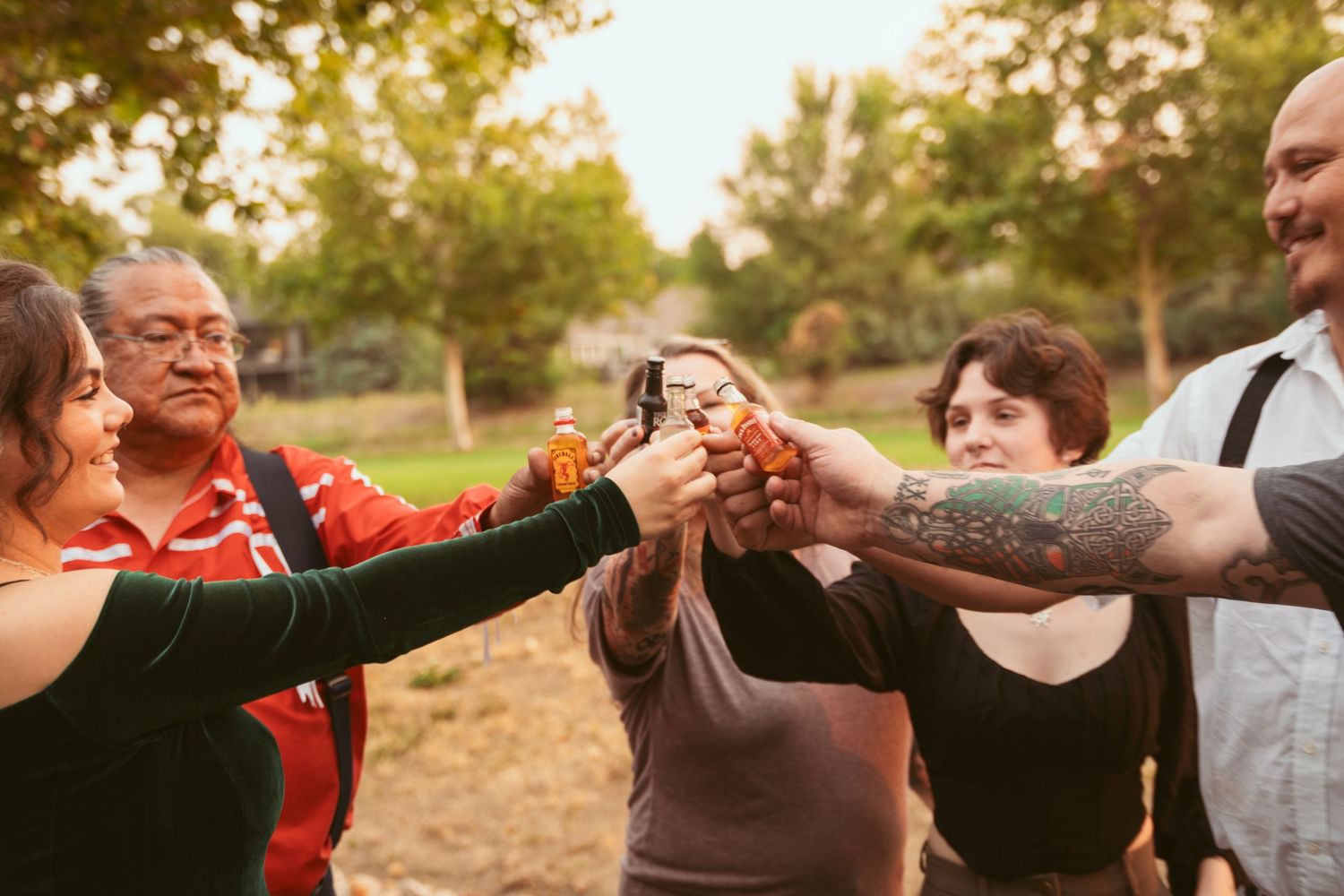 Friends toasting and raising their drinks together in an outdoor gathering.
