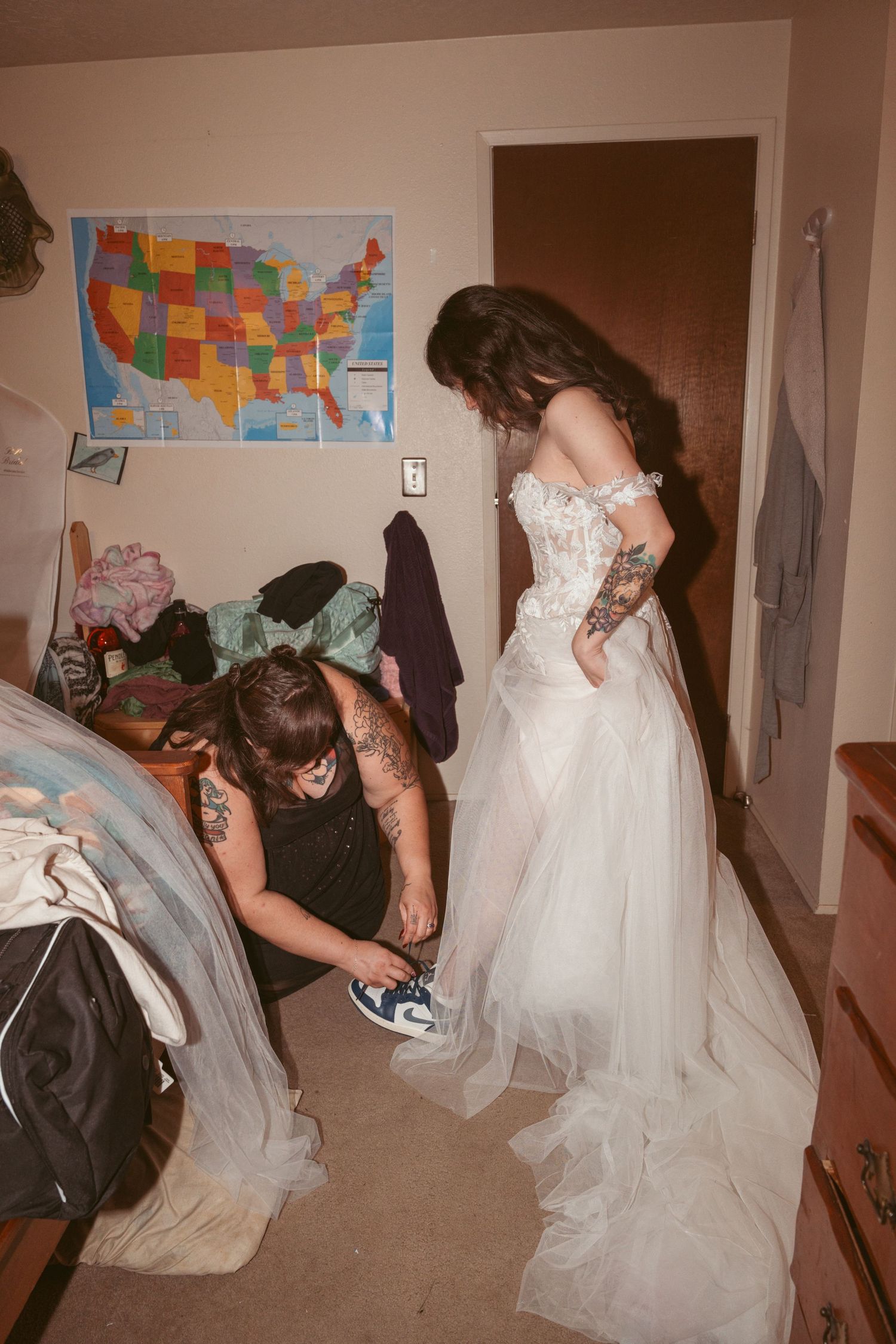 Wedding dress being adjusted and bustled in a room with a US map on the wall.