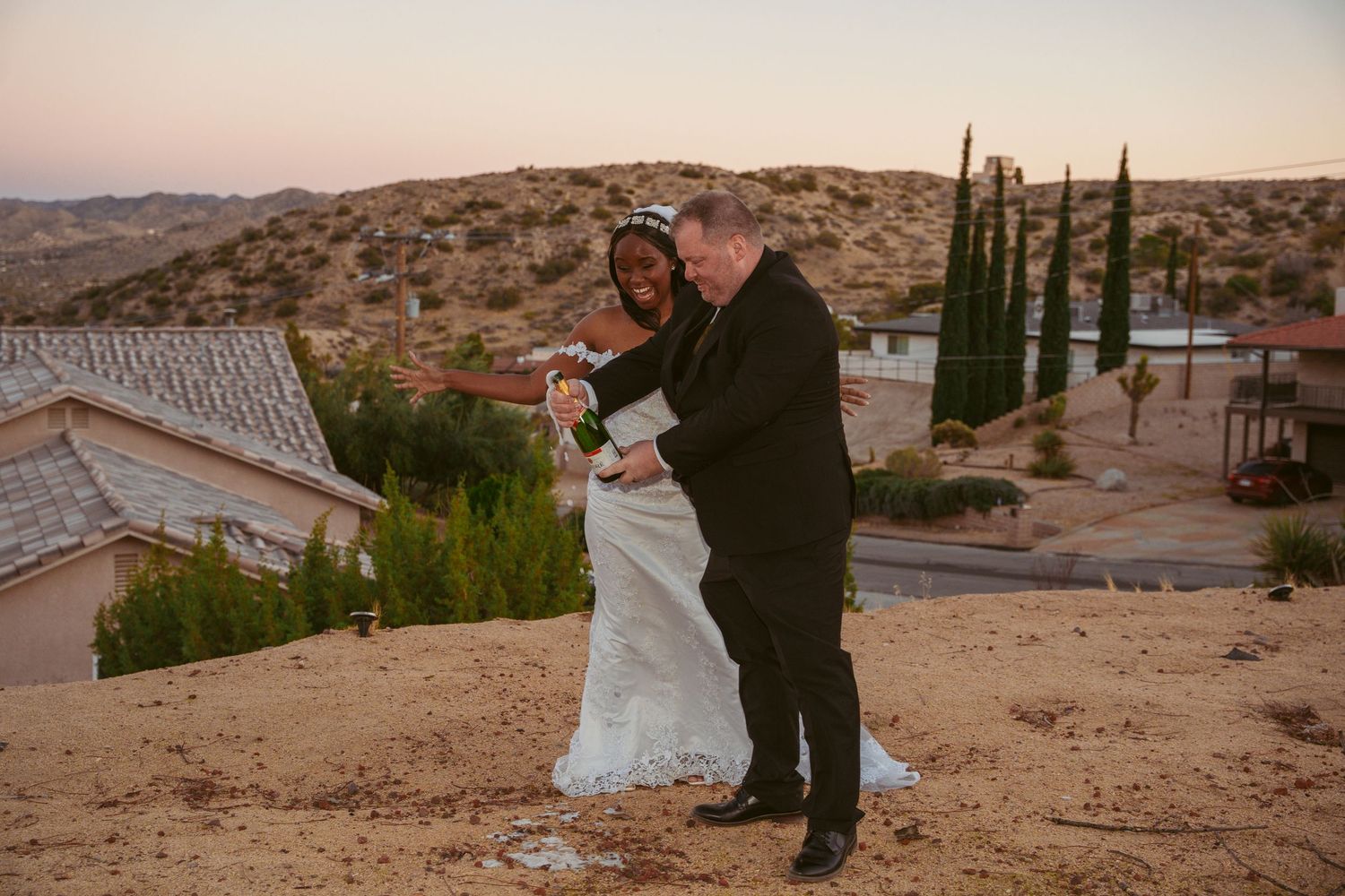 A playful wedding moment captured against a desert backdrop at sunset.