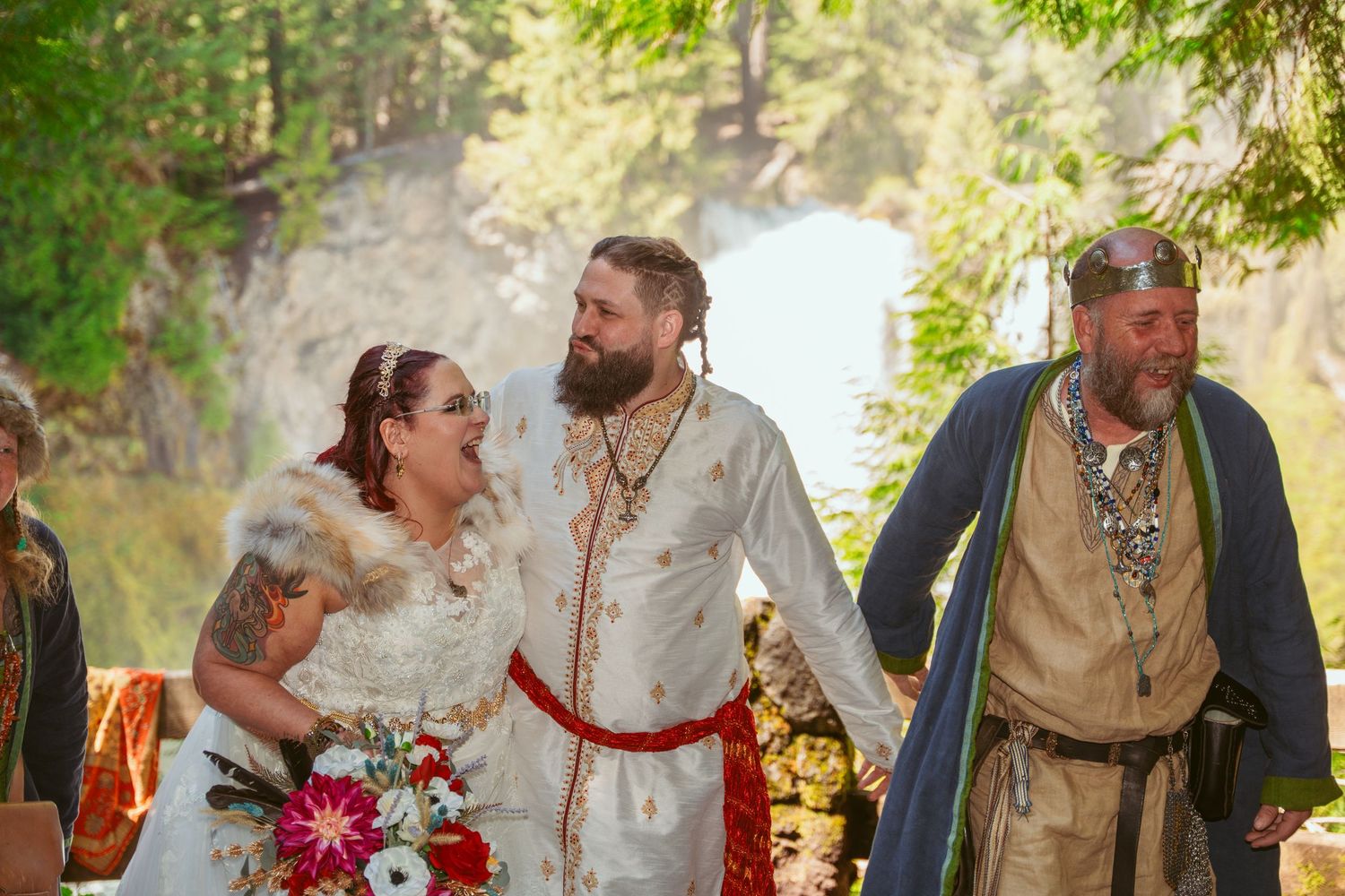 Wedding guests in medieval-inspired clothing celebrate during an outdoor forest ceremony.