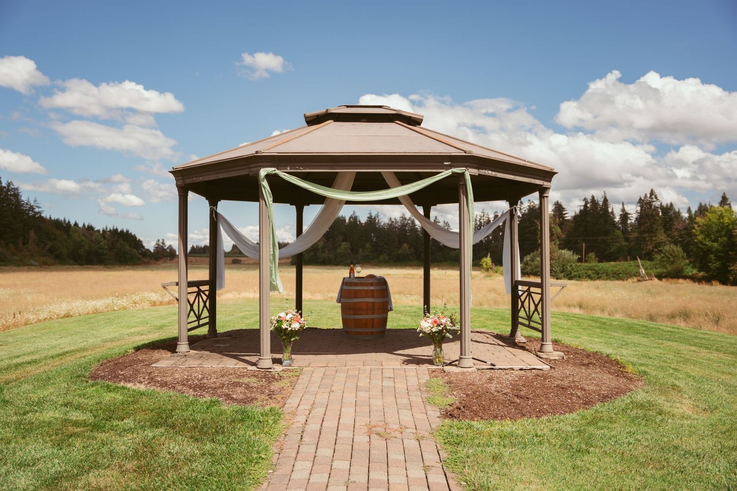 Panoramic view of an outdoor wedding pavilion set against rolling hills and blue sky.