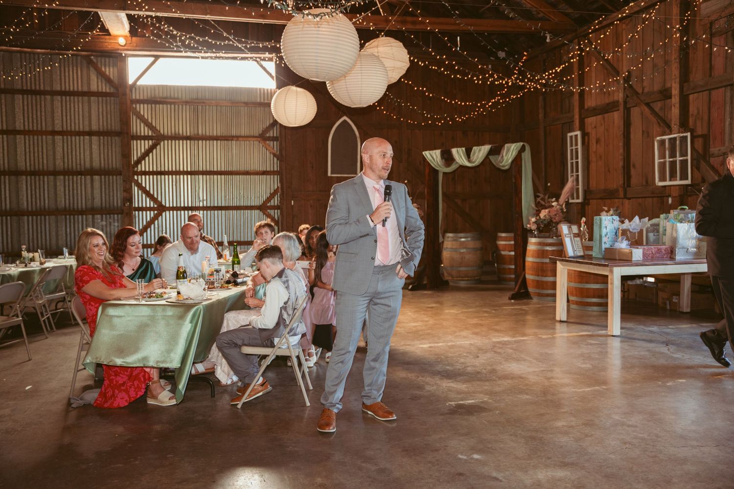 Wedding celebration in a rustic barn venue with guests seated at decorated tables.