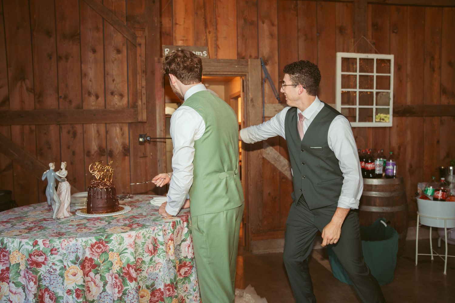 Wedding couple enjoys a fun cake-feeding moment in a barn venue.