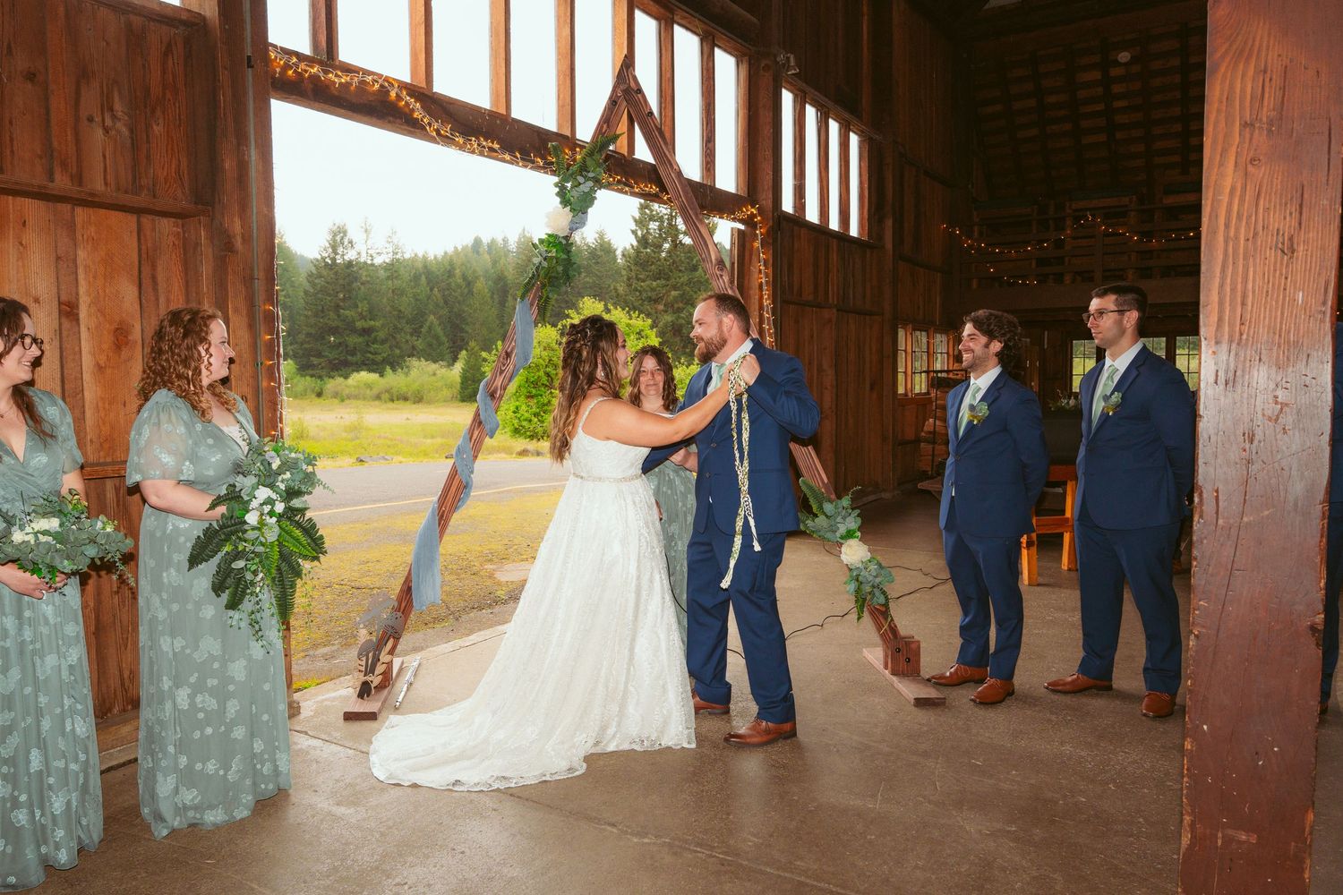 Panoramic view of barn wedding ceremony showing full length of venue and gathered guests.