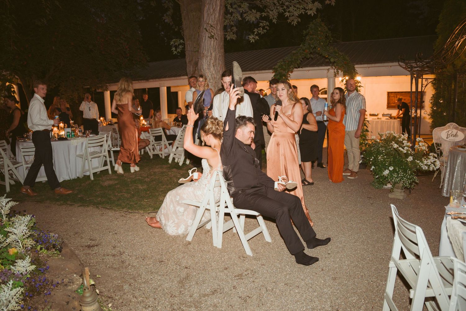 Wedding guests participate in a fun chair-lifting tradition during an outdoor evening reception.