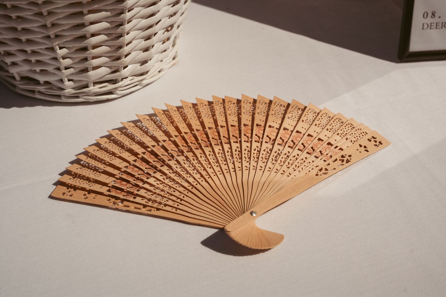 Decorative wooden folding fans displayed on a light gray surface.