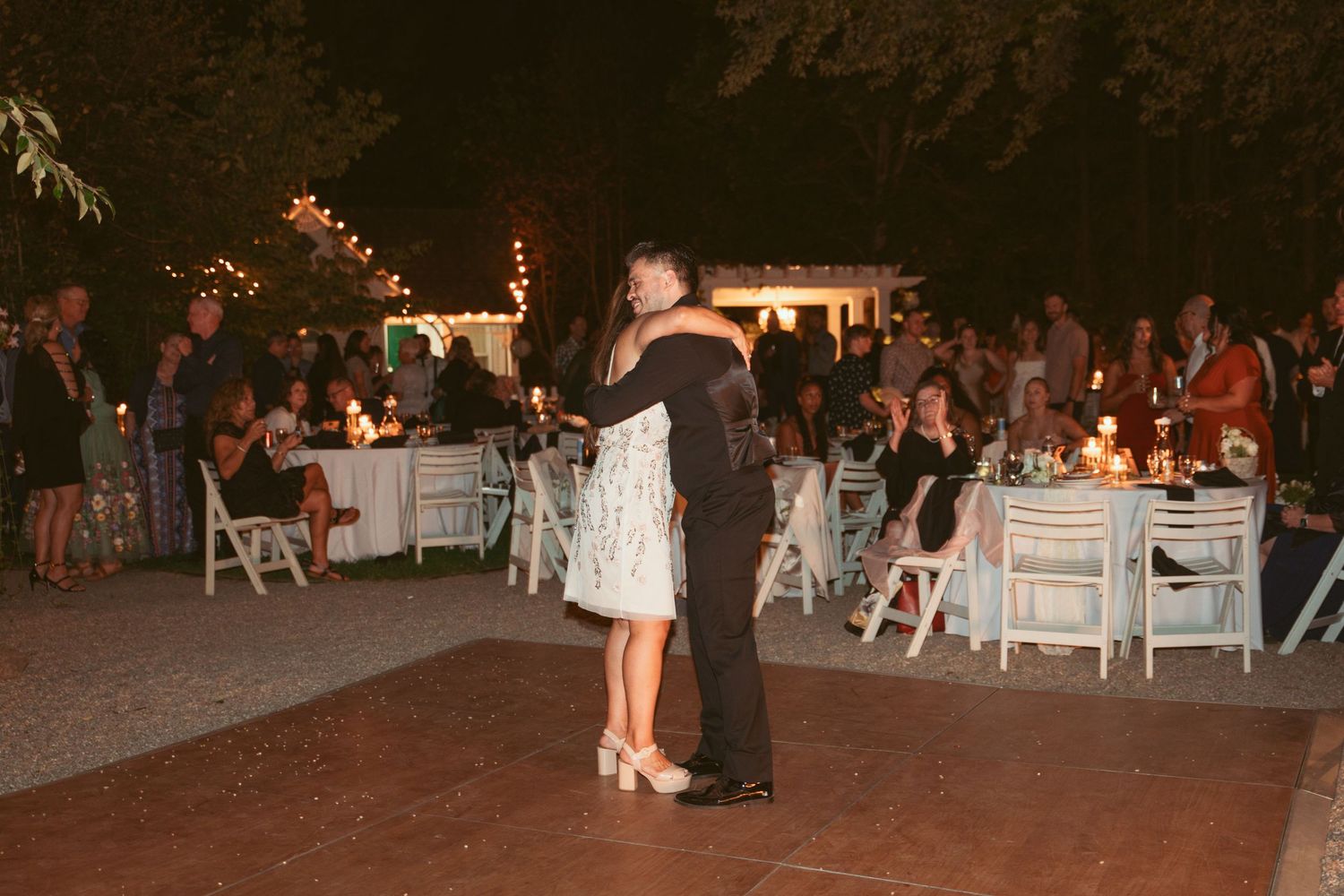 A couple sharing a romantic dance moment on the outdoor reception dance floor at night.