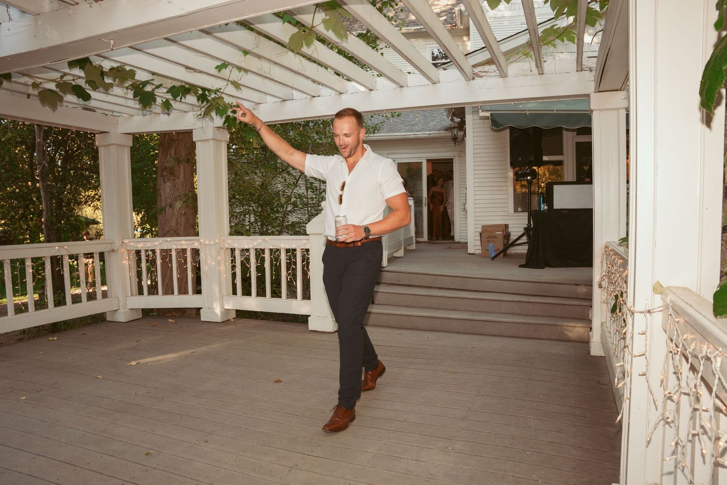 A person dances on a white covered porch with elegant columns and a pergola overhead.