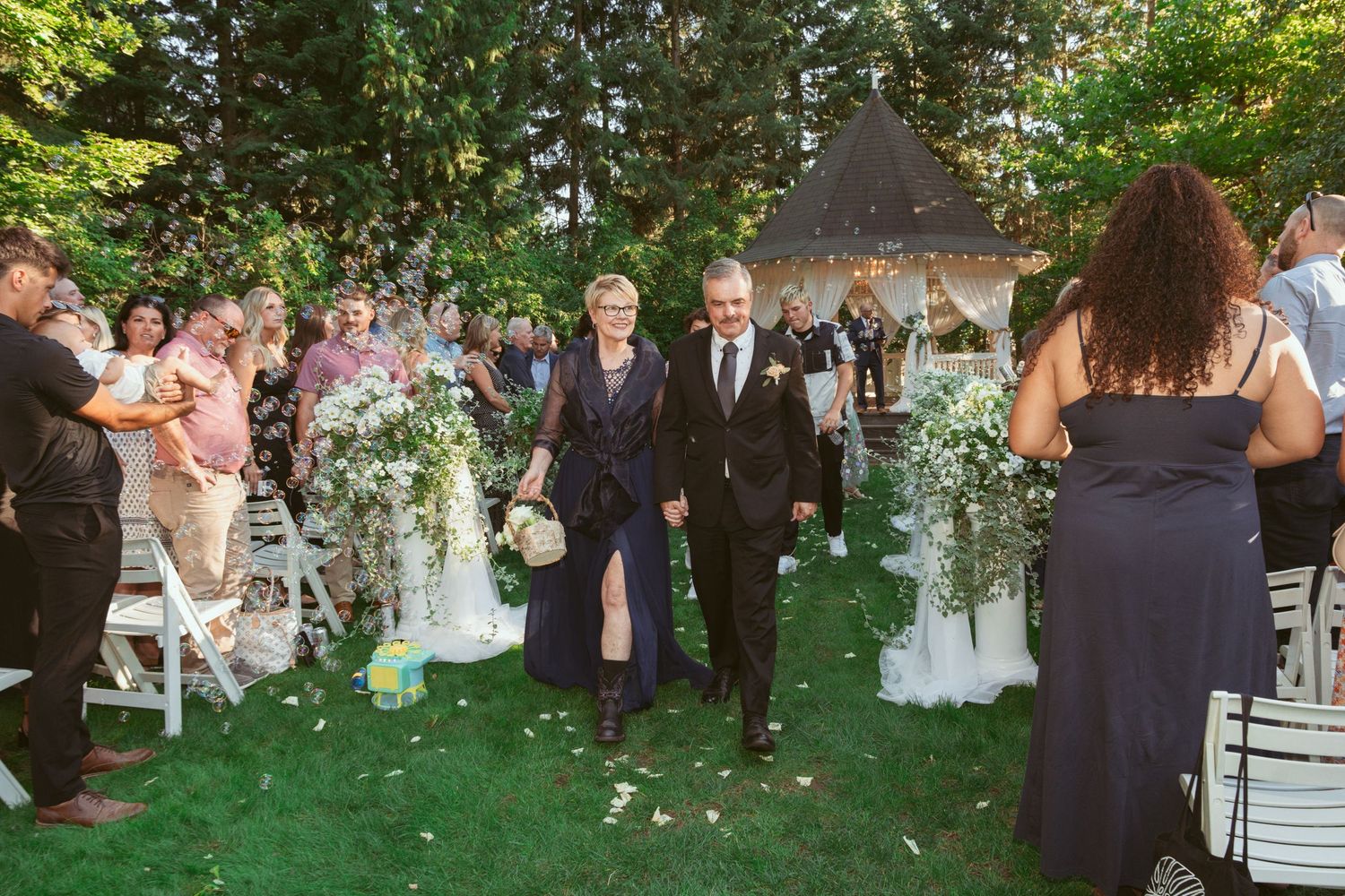 Celebratory group dance taking place on a manicured lawn during an outdoor summer wedding reception.