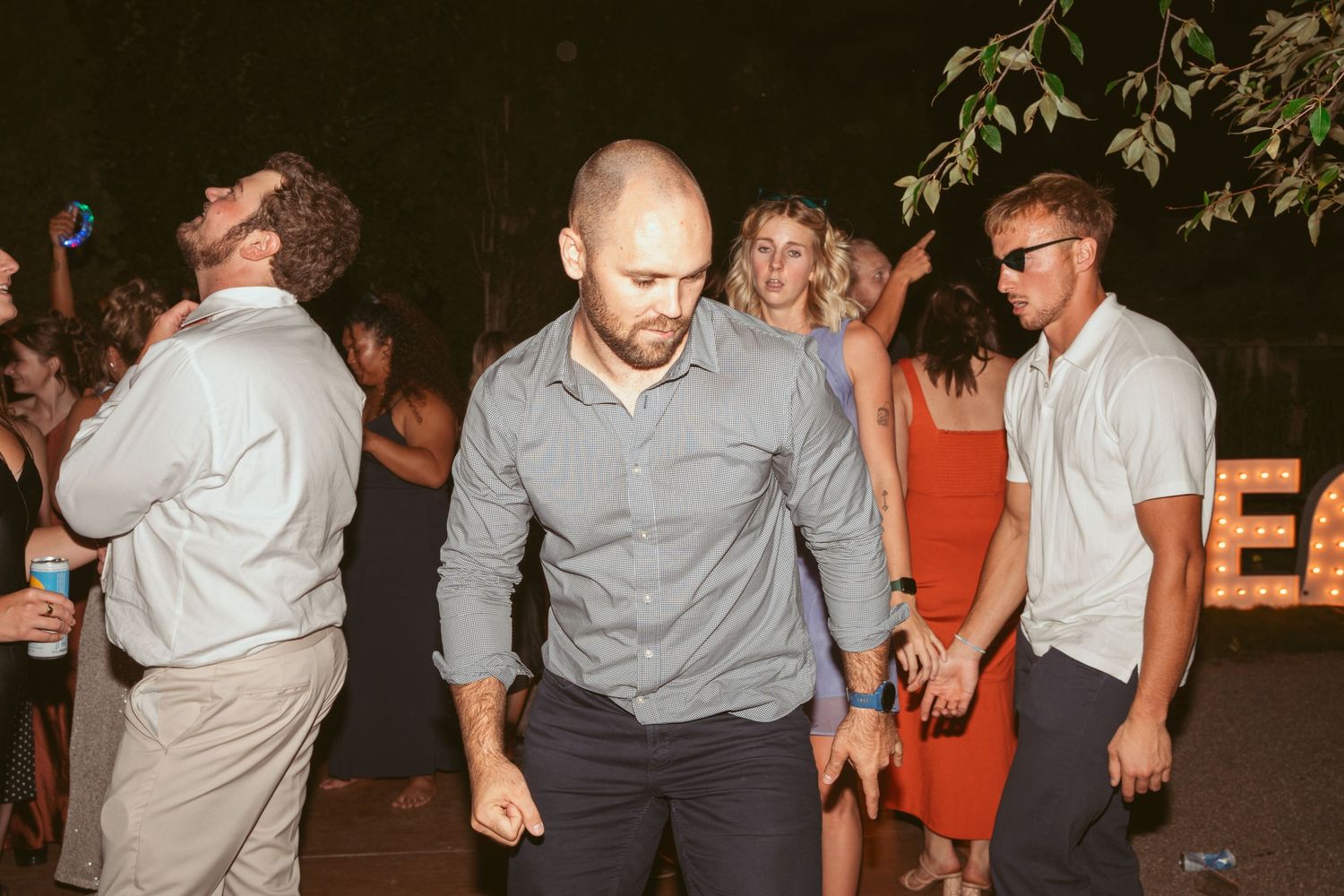 Party guests dancing and celebrating at an outdoor nighttime event.