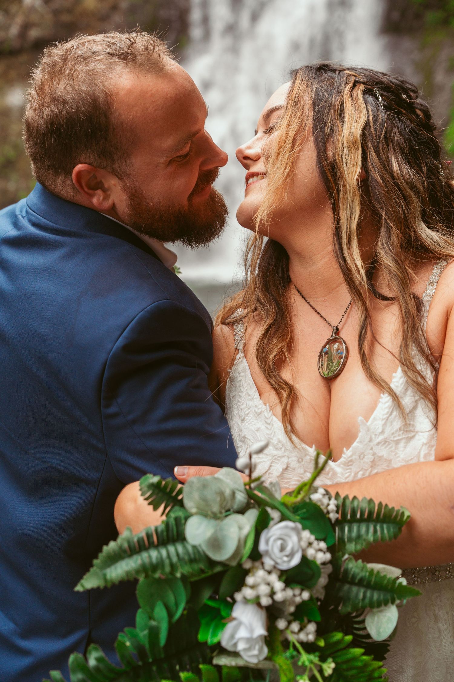 Romantic wedding portraits captured against scenic waterfall backdrop.