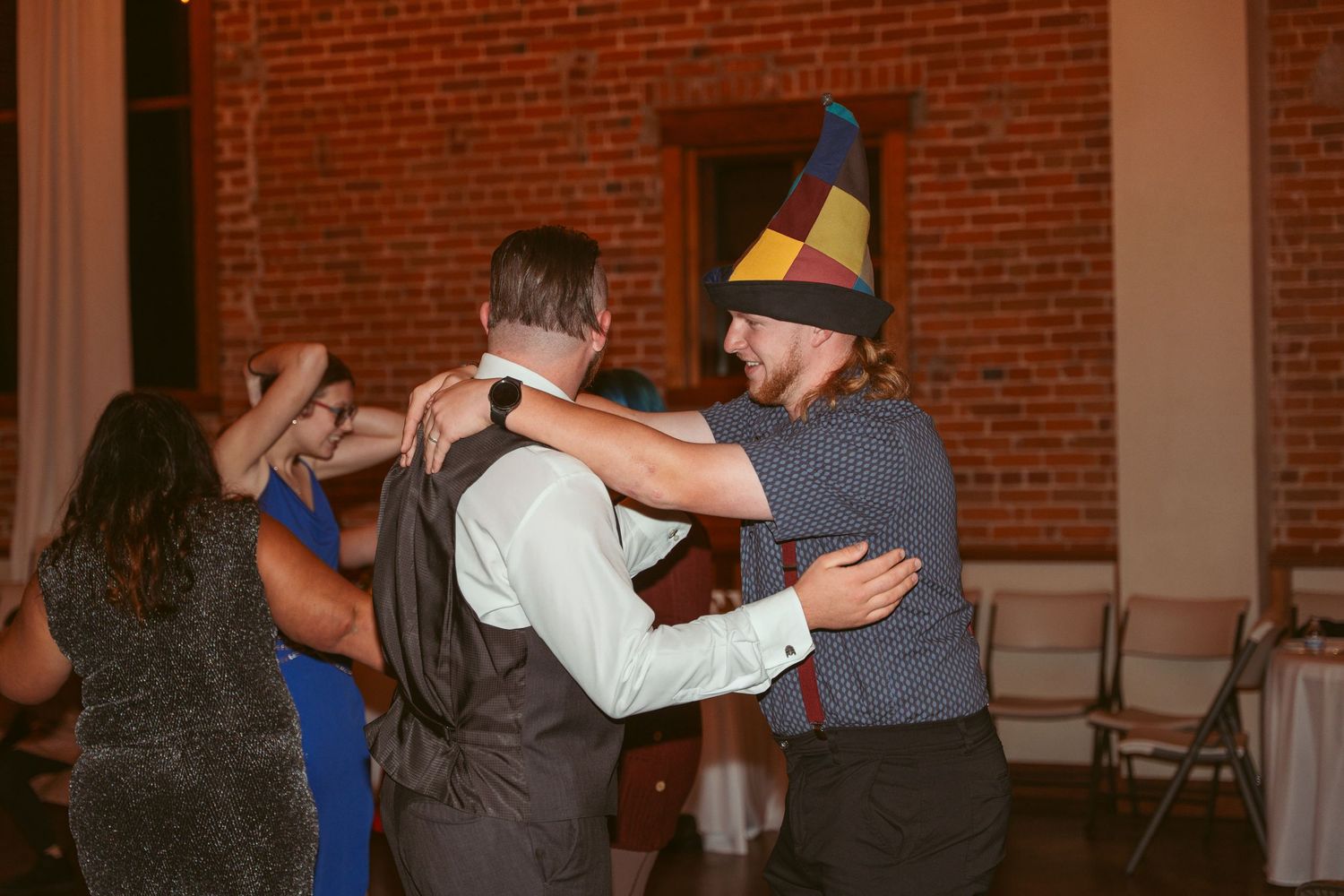 Couples slow dancing together in a dimly lit brick venue during an evening celebration.